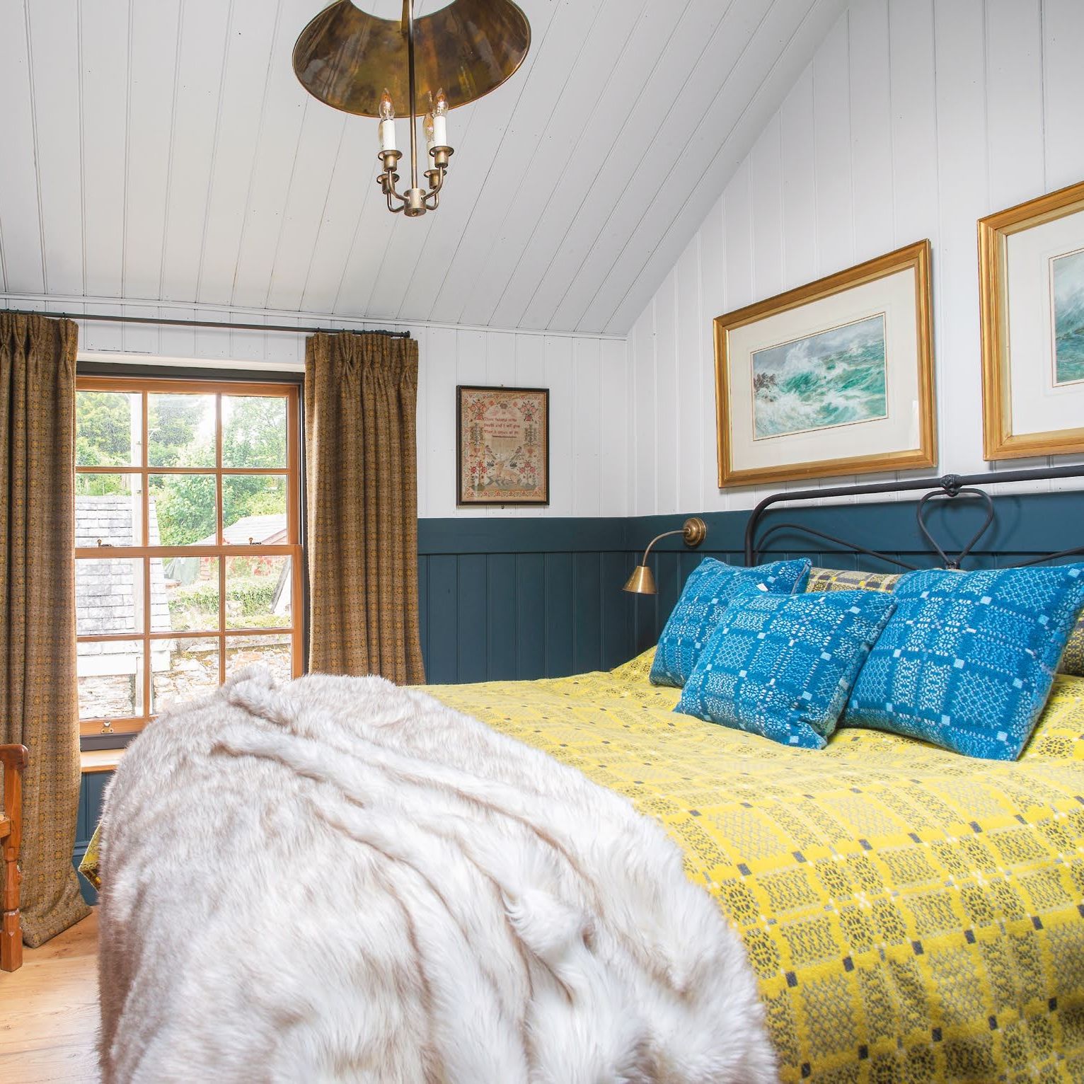 cottage bedroom with dark blue painted tongue &amp;amp; groove panelling and traditional welsh bed throw and cushions