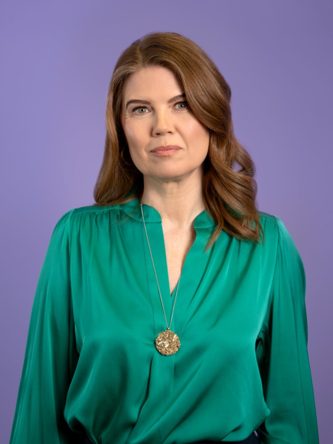 A woman in a green shirt against a purple background