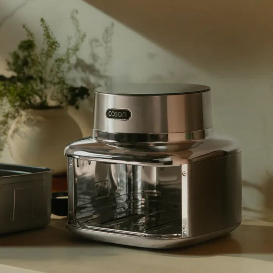 Stainless steel Cosori air fryer and its air fryer drawer sitting on a kitchen counter
