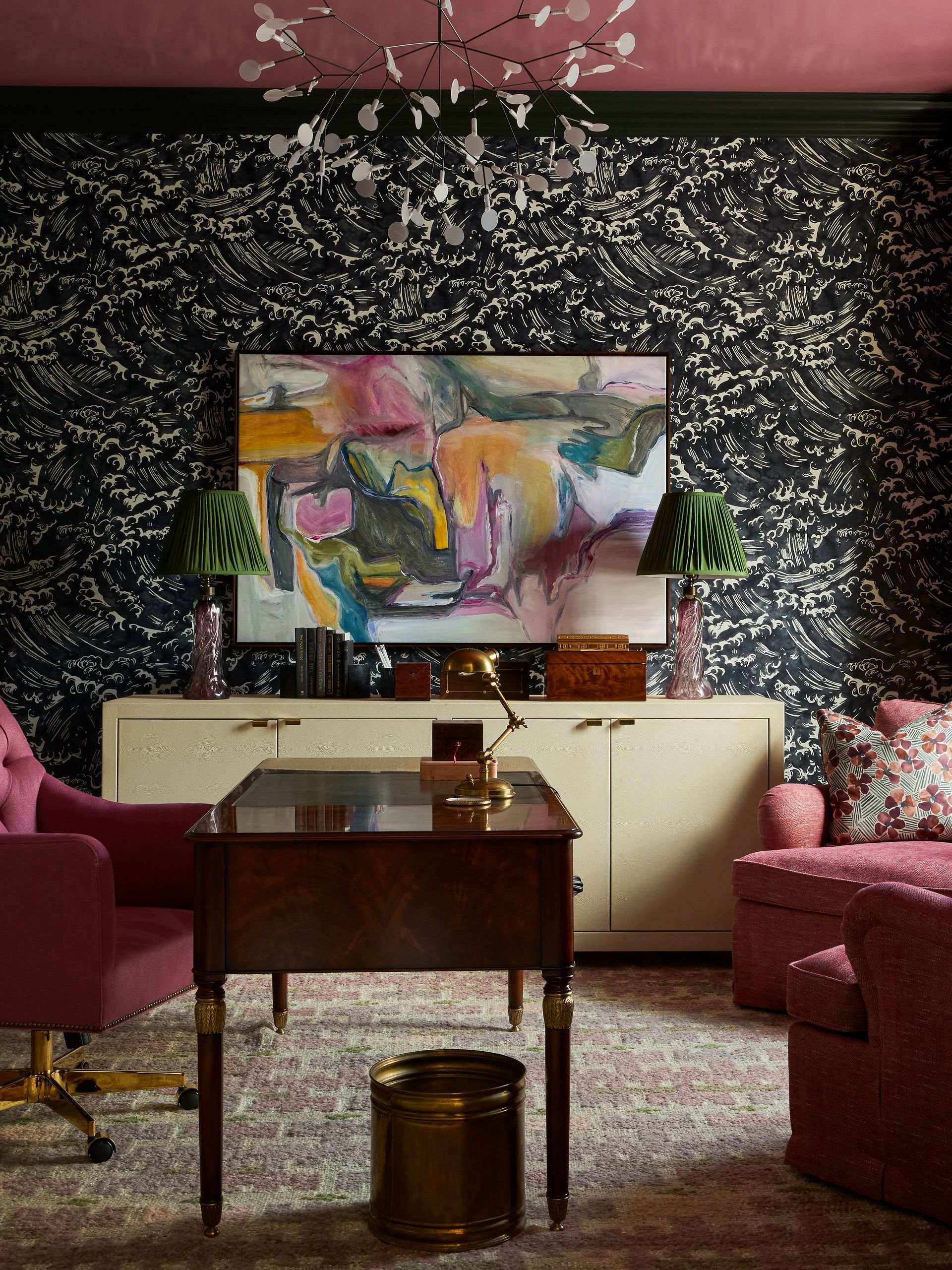 A home office with pink accents, all backed by a darkly patterned wallpaper that behaves like a neutral.