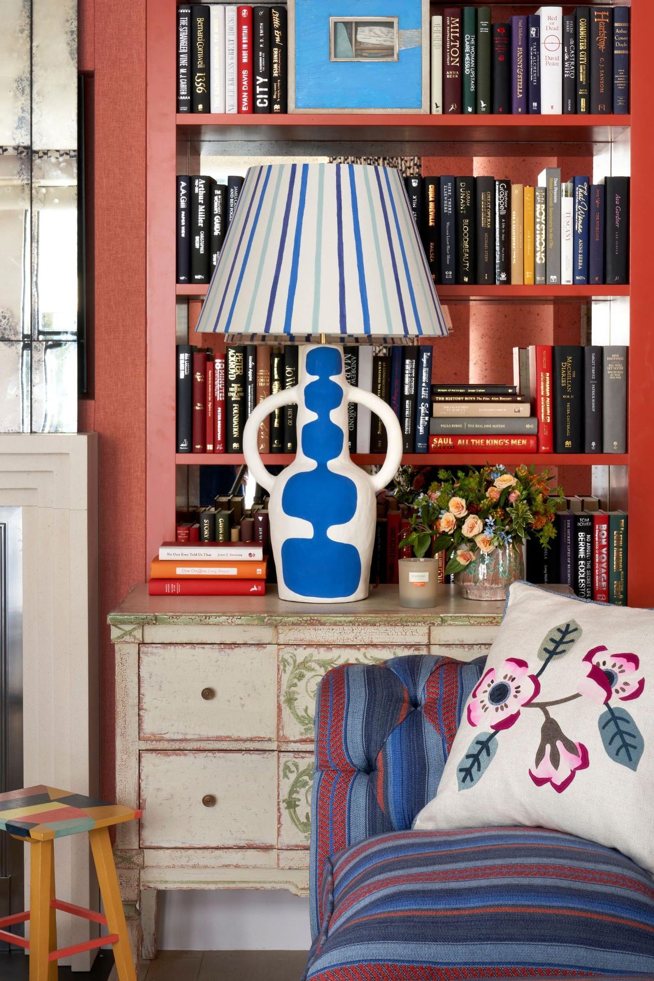red living room alcove with built in bookcase styled with a blue and white striped lamp
