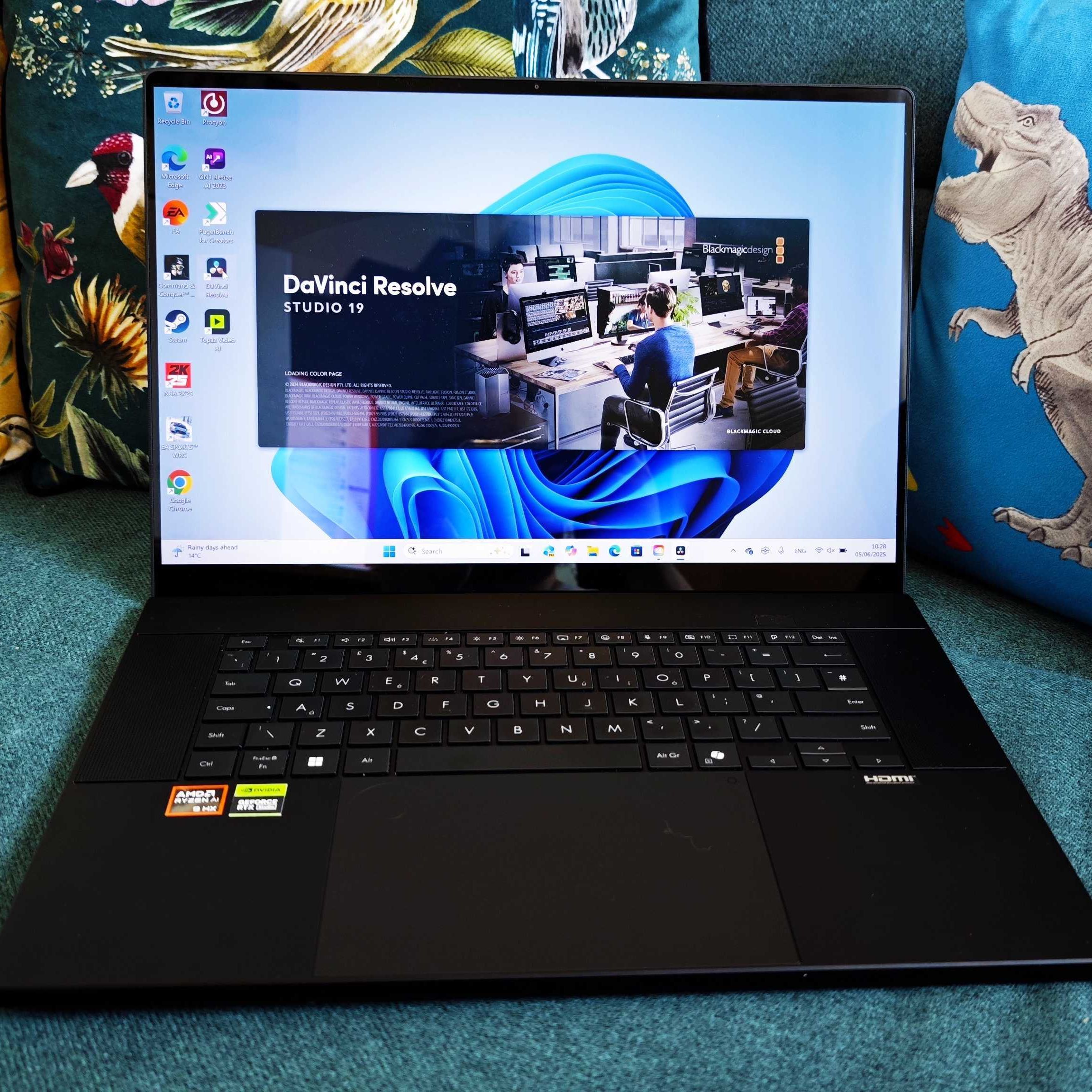 A black ASUS ProArt P16 laptop on a green sofa