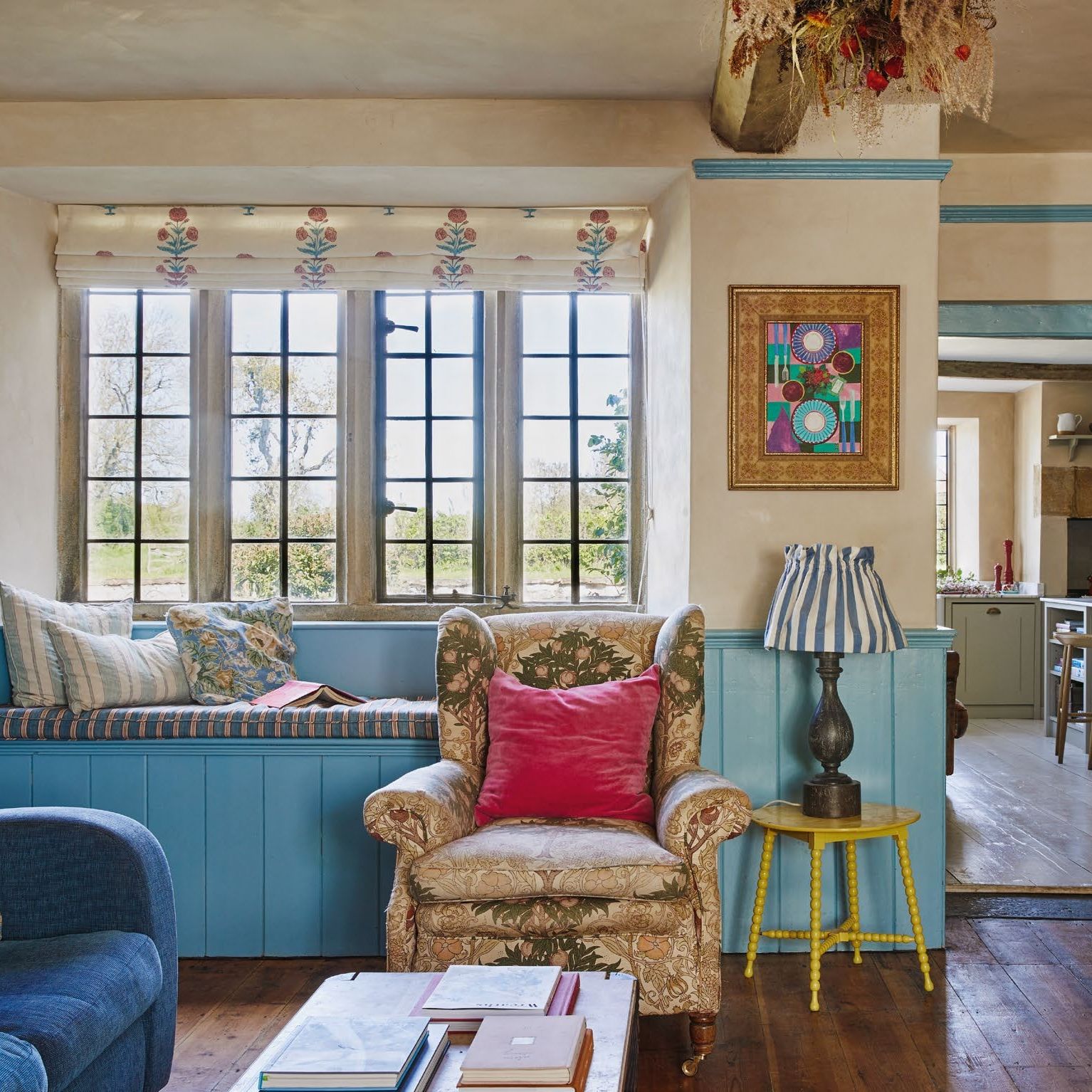view towards window seat in a snug with leaded windows and floral blind, and doorway through to kitchen
