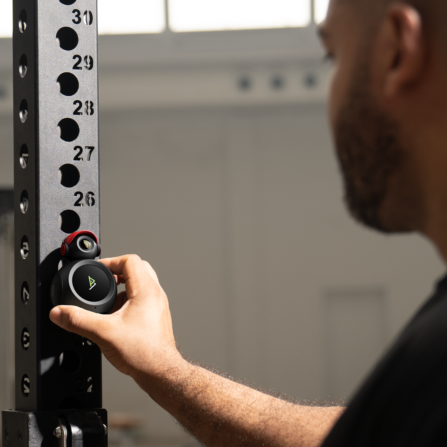 Camera mounted on top of a circular screen, being attached to a squat rack by a man