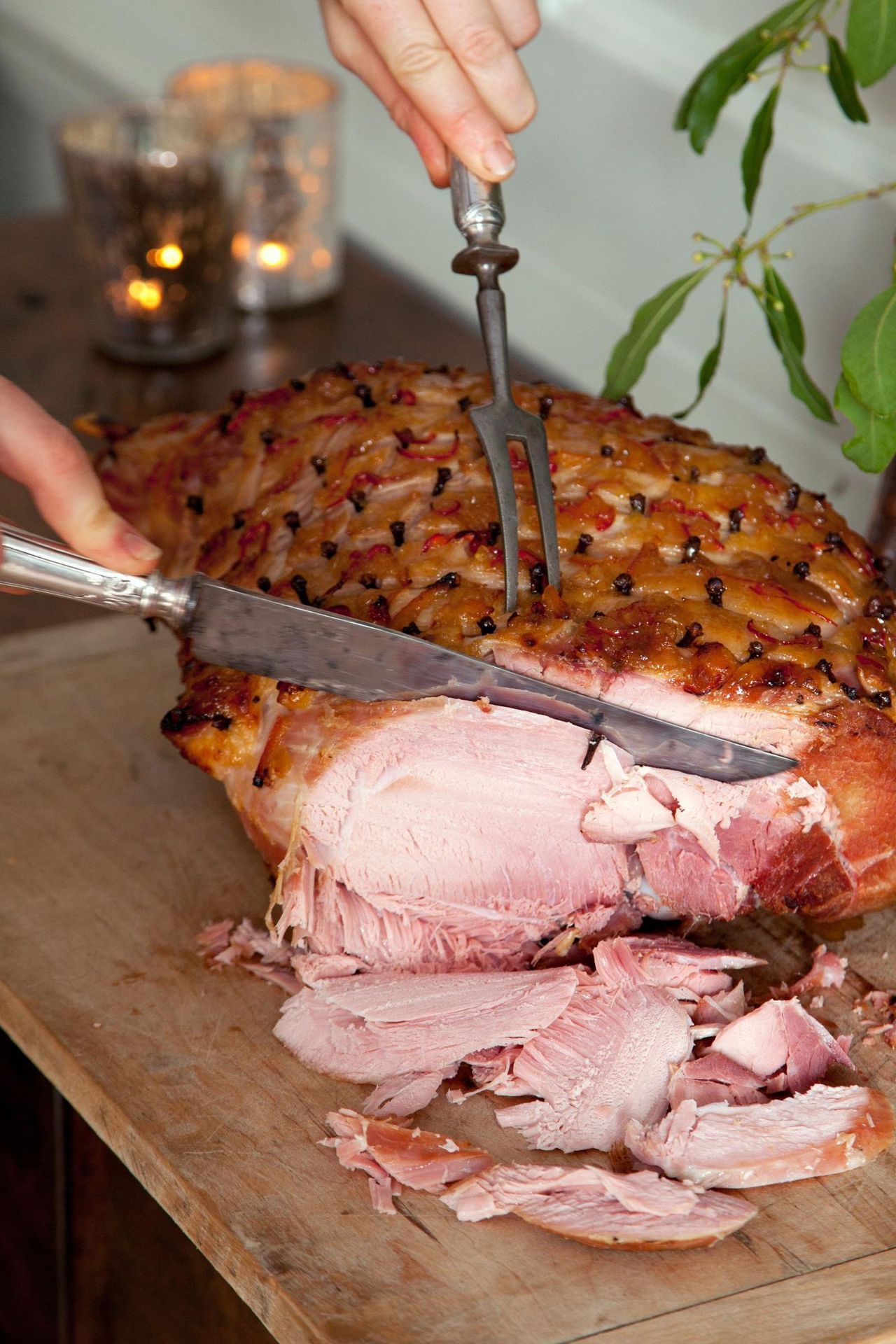 Someone cutting a Christmas ham on a wooden board