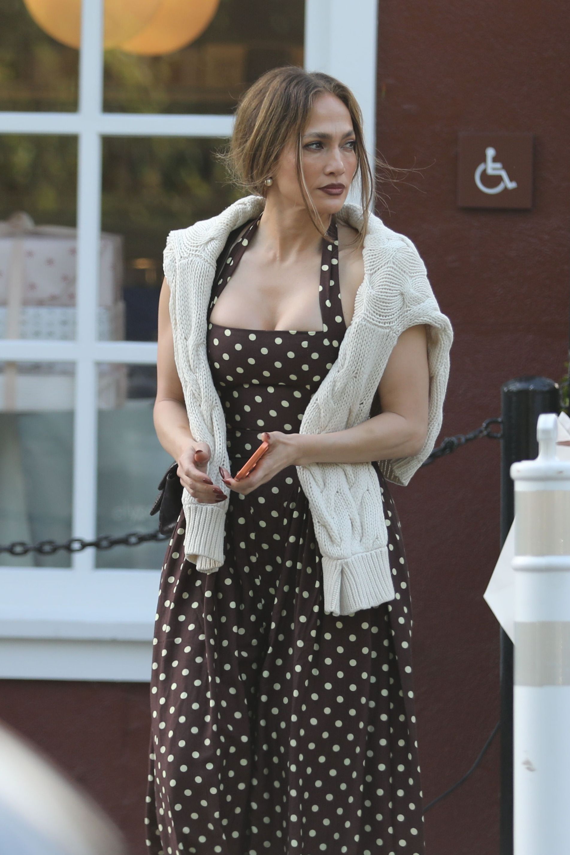 jlo wears a polka dot dress and knit sweater