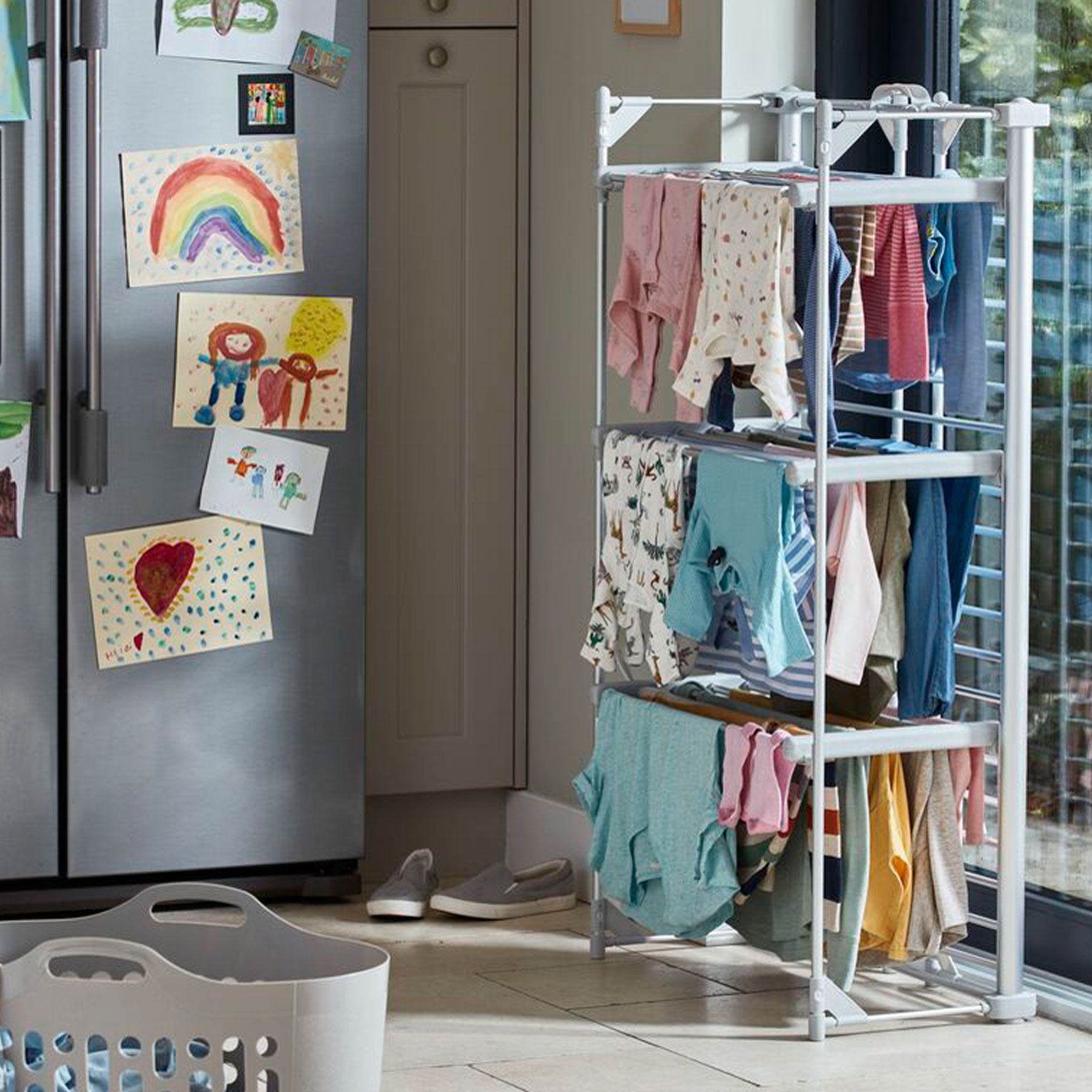 heated clothes airer full of clothes positioned in kitchen next to large fridge and window