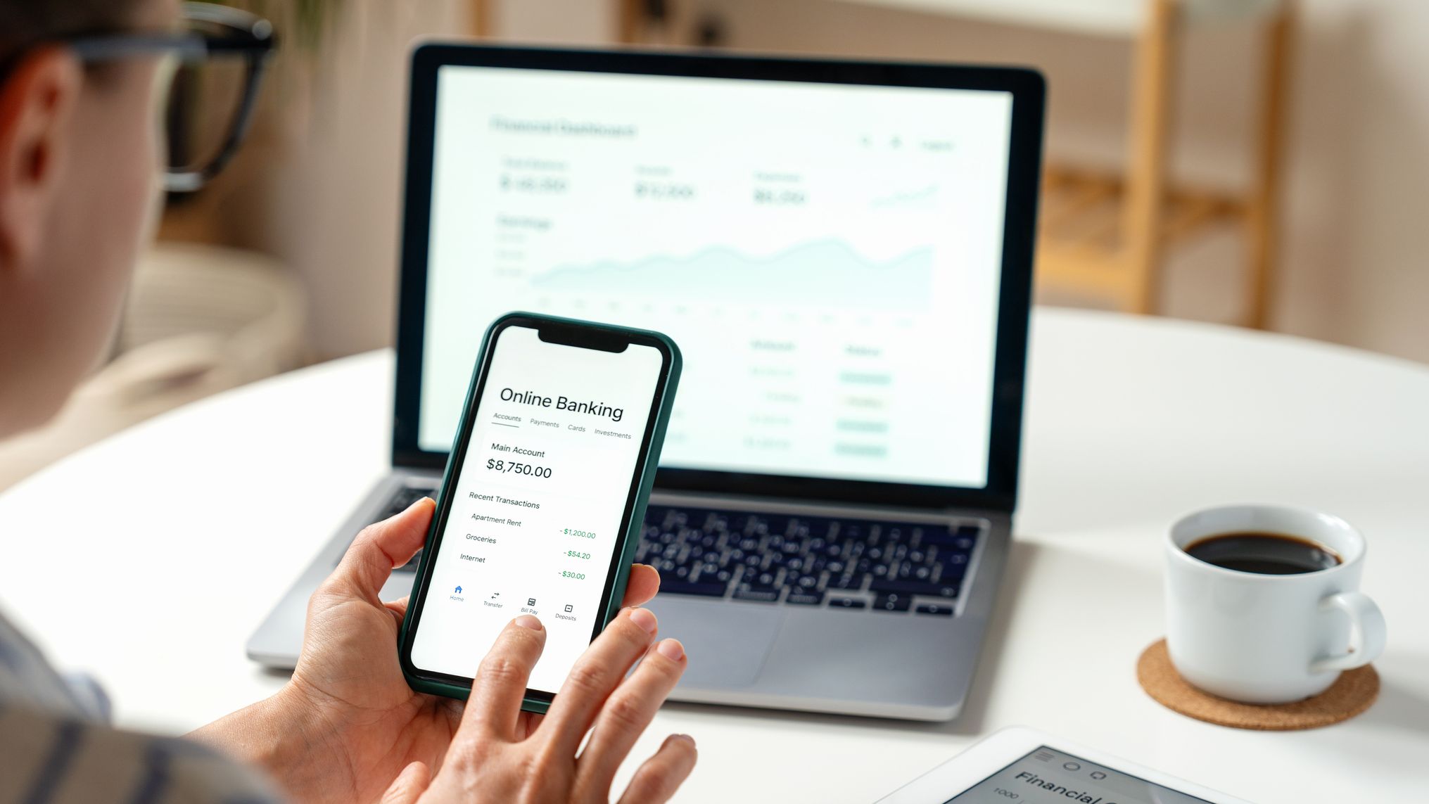 User accessing digital banking services via smartphone and laptop at home