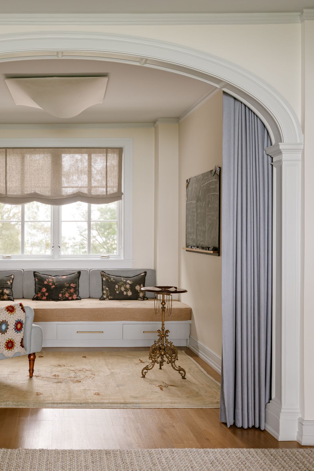 Light, airy sitting room featuring upholstered furniture, baby blue curtains, and an antique side table