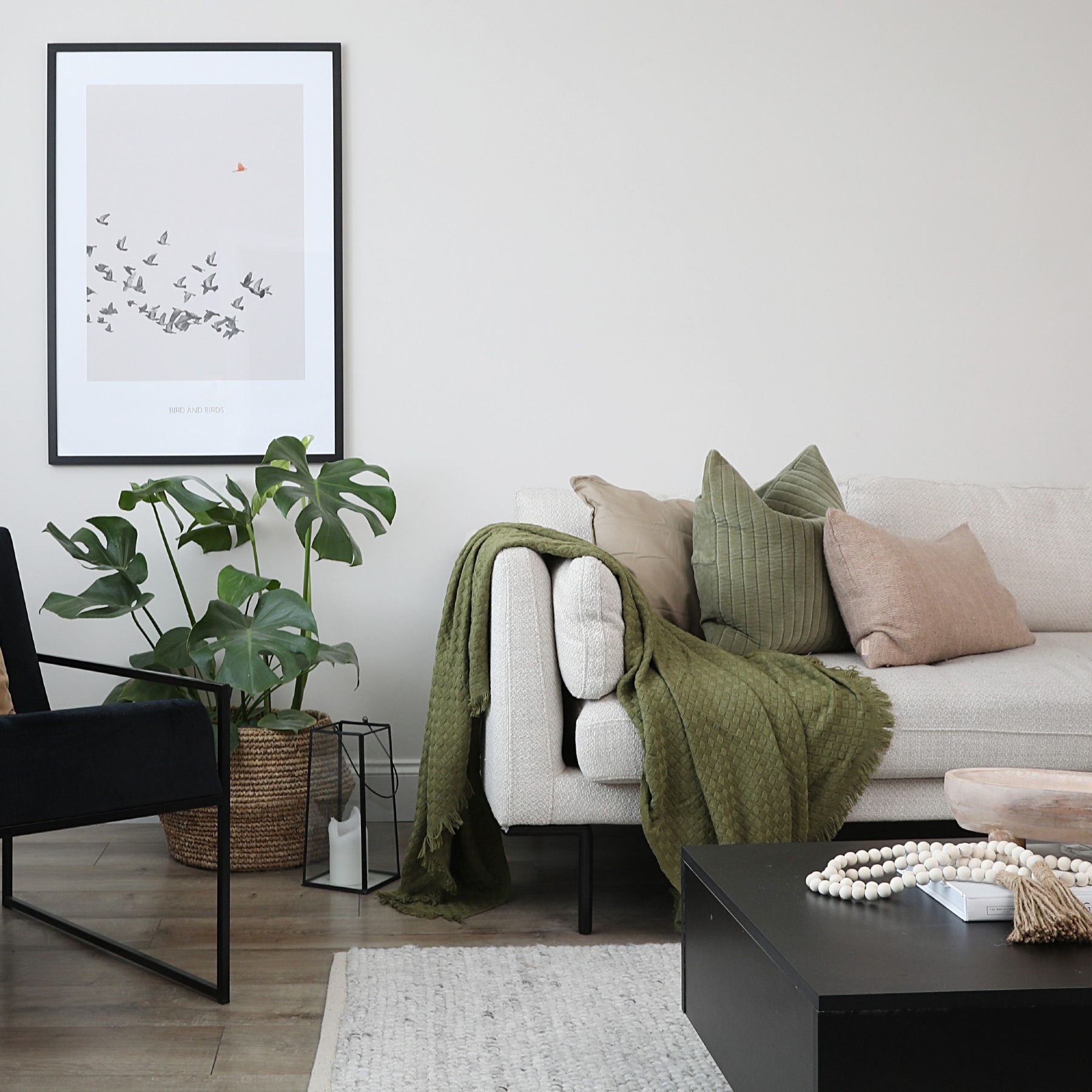 An off-white living room with a beige sofa, a black accent chair and a matching coffee table
