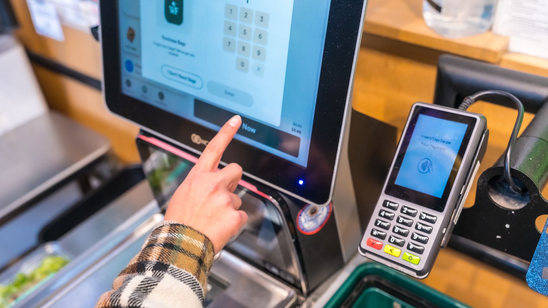 Customer using self-checkout kiosk at grocery store