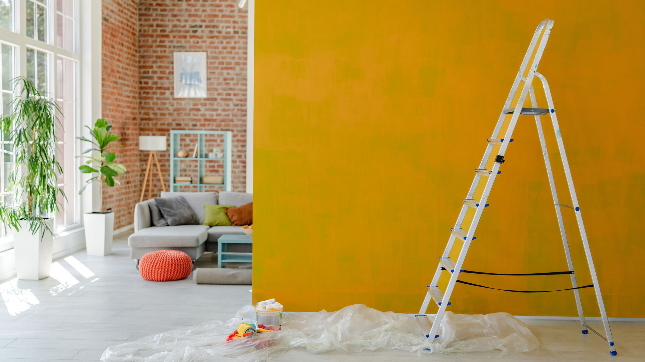 Ladder placed beside a vibrant yellow wall mid-paint