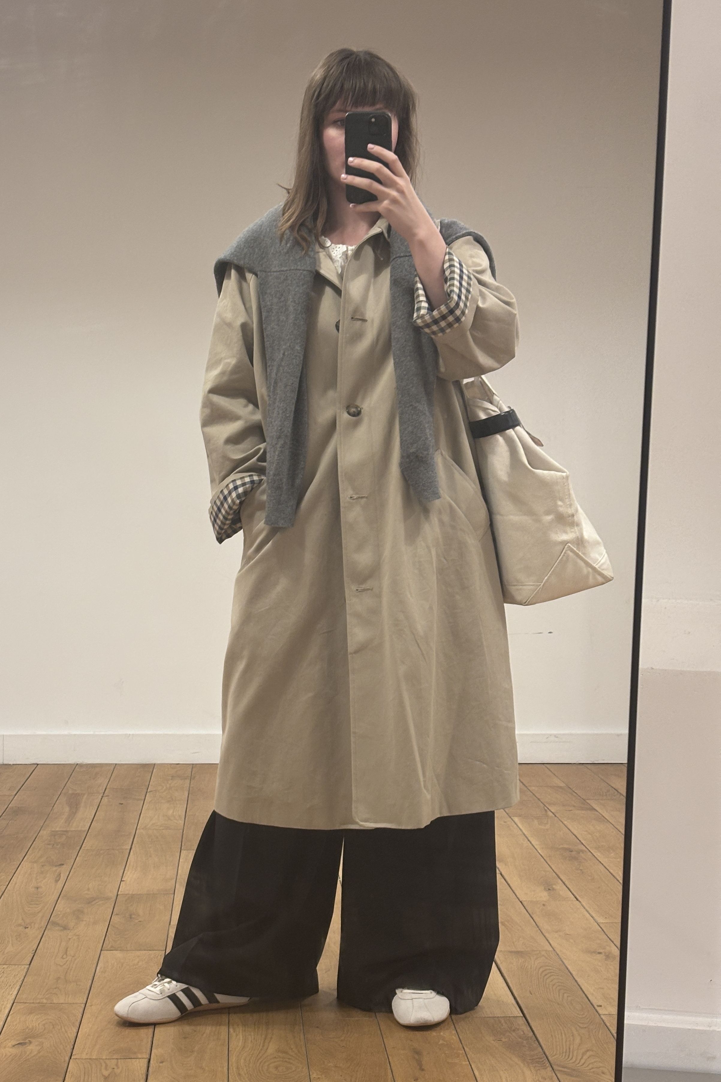 Halie LeSavage wearing white adidas Toyko sneakers, black pants, and a tan trench coat