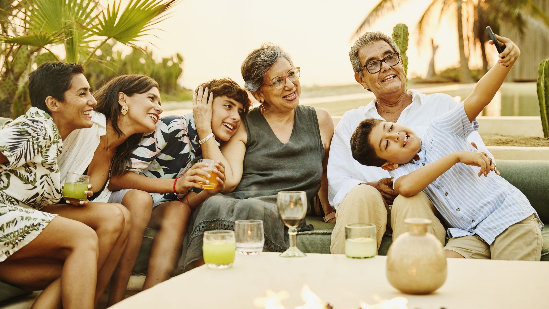 Grandson taking a group selfie of his family on vacation at luxury beach resort at sunset