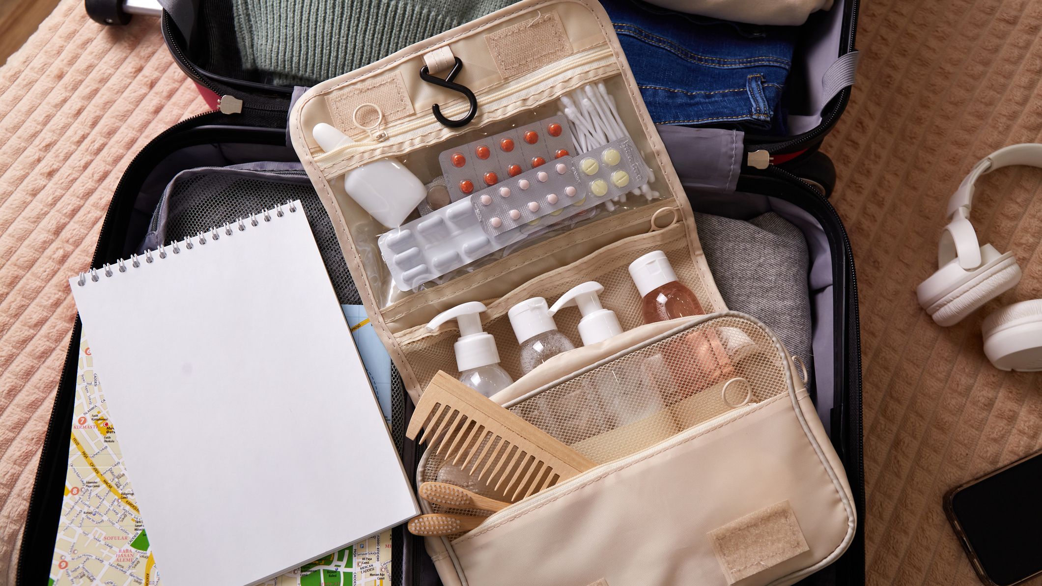 Open suitcase packed with clothing, toiletries, and travel essentials ready for a trip