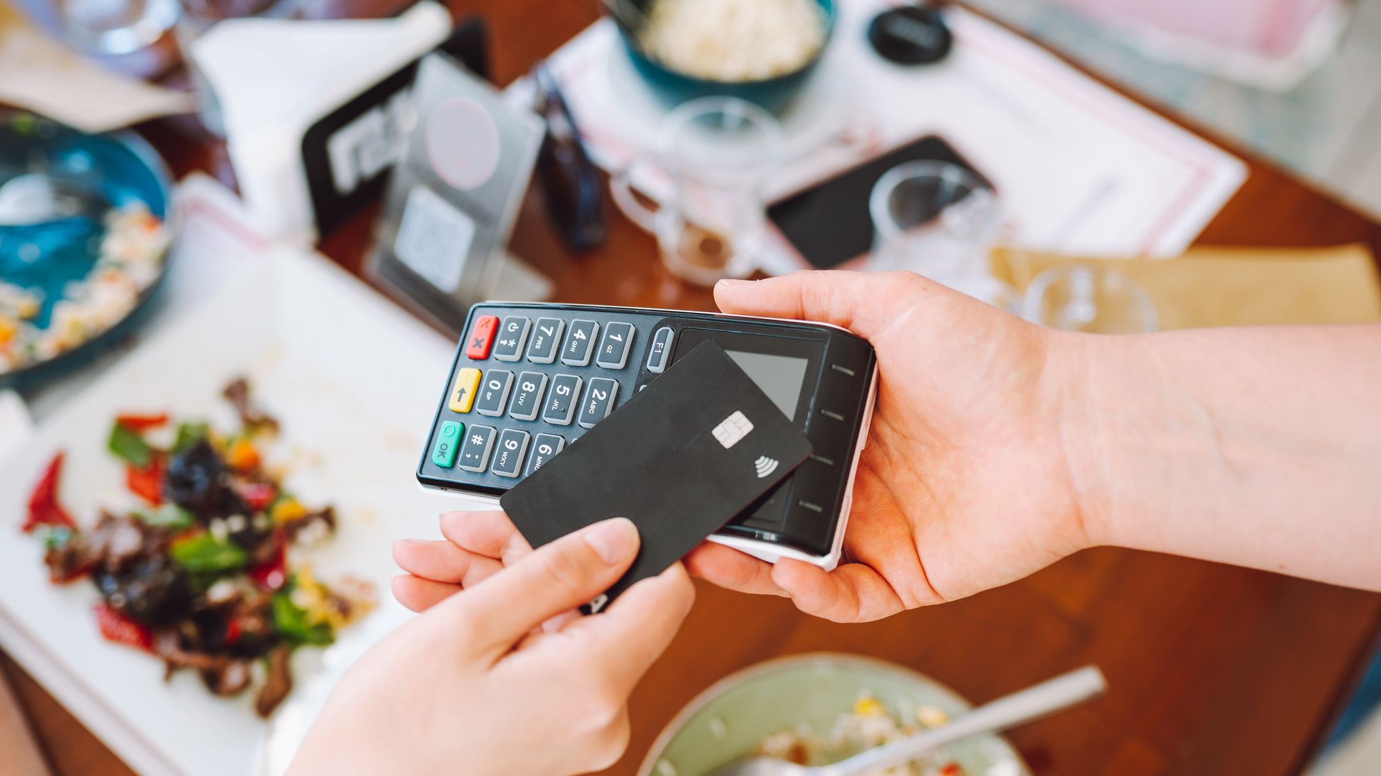 A person tapping their credit card to pay for their meal.