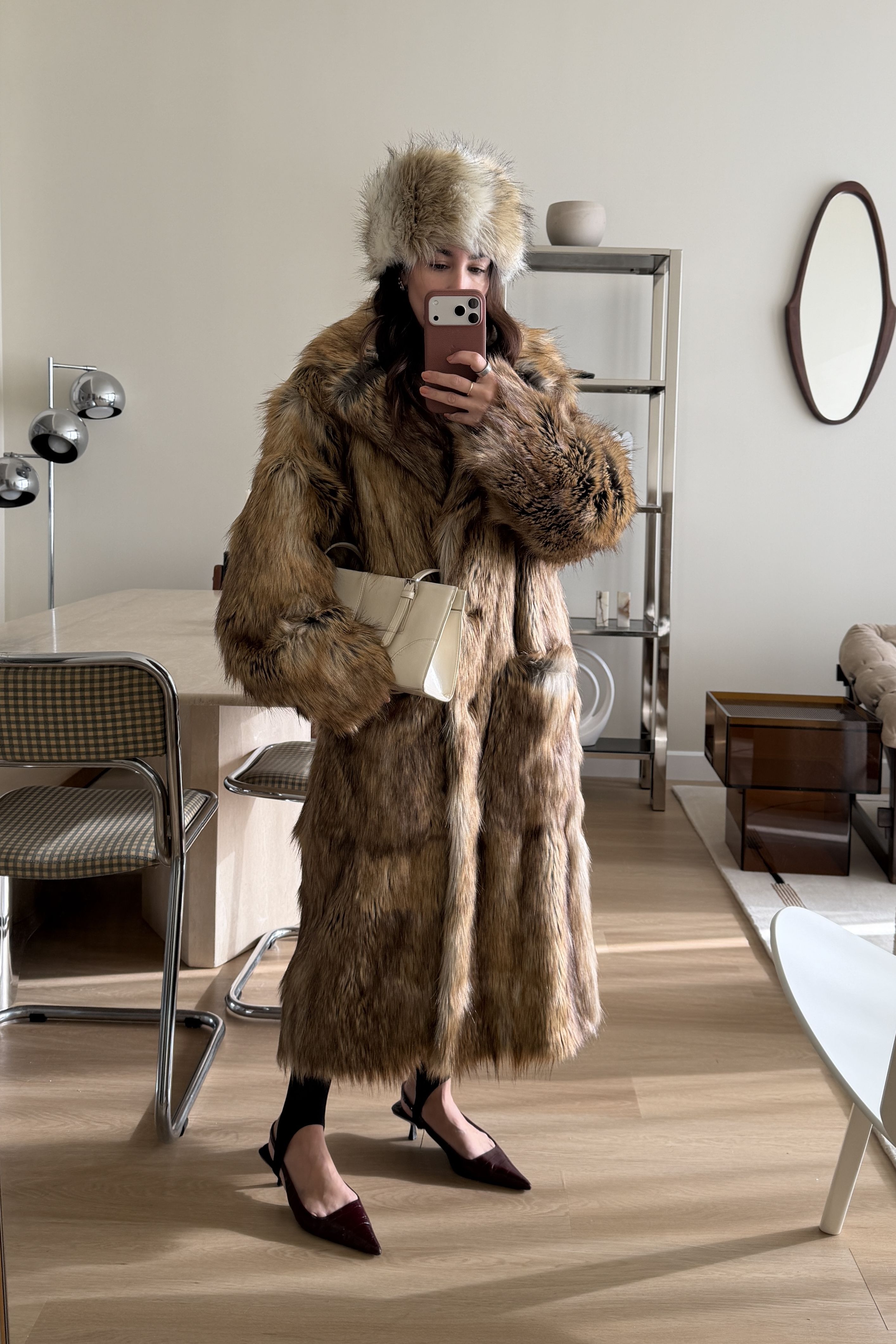 Lauren Caruso posing in mirror wearing fur hat, fur coat, and heels