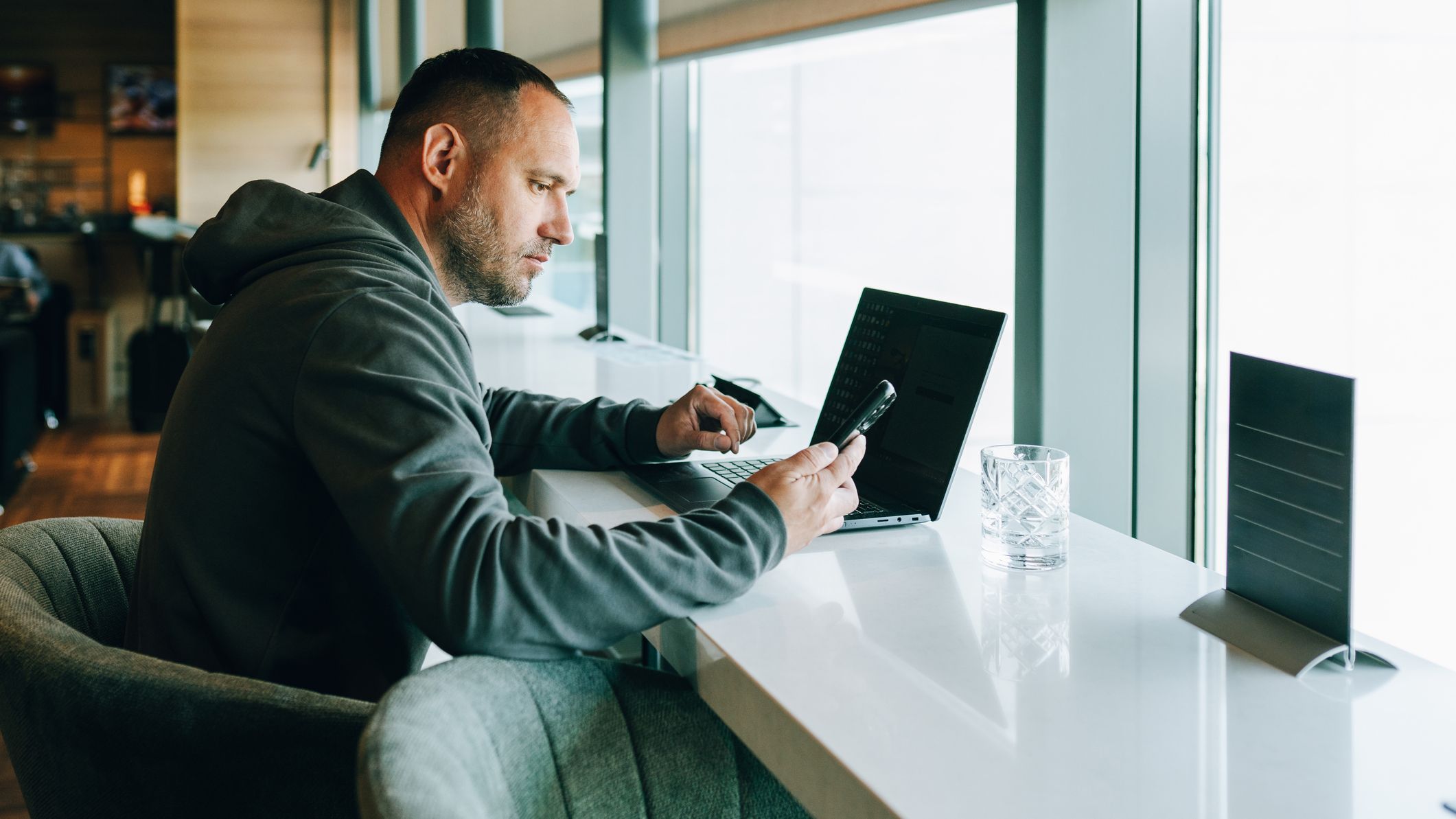 Man working on laptop and smartphone in airport lounge