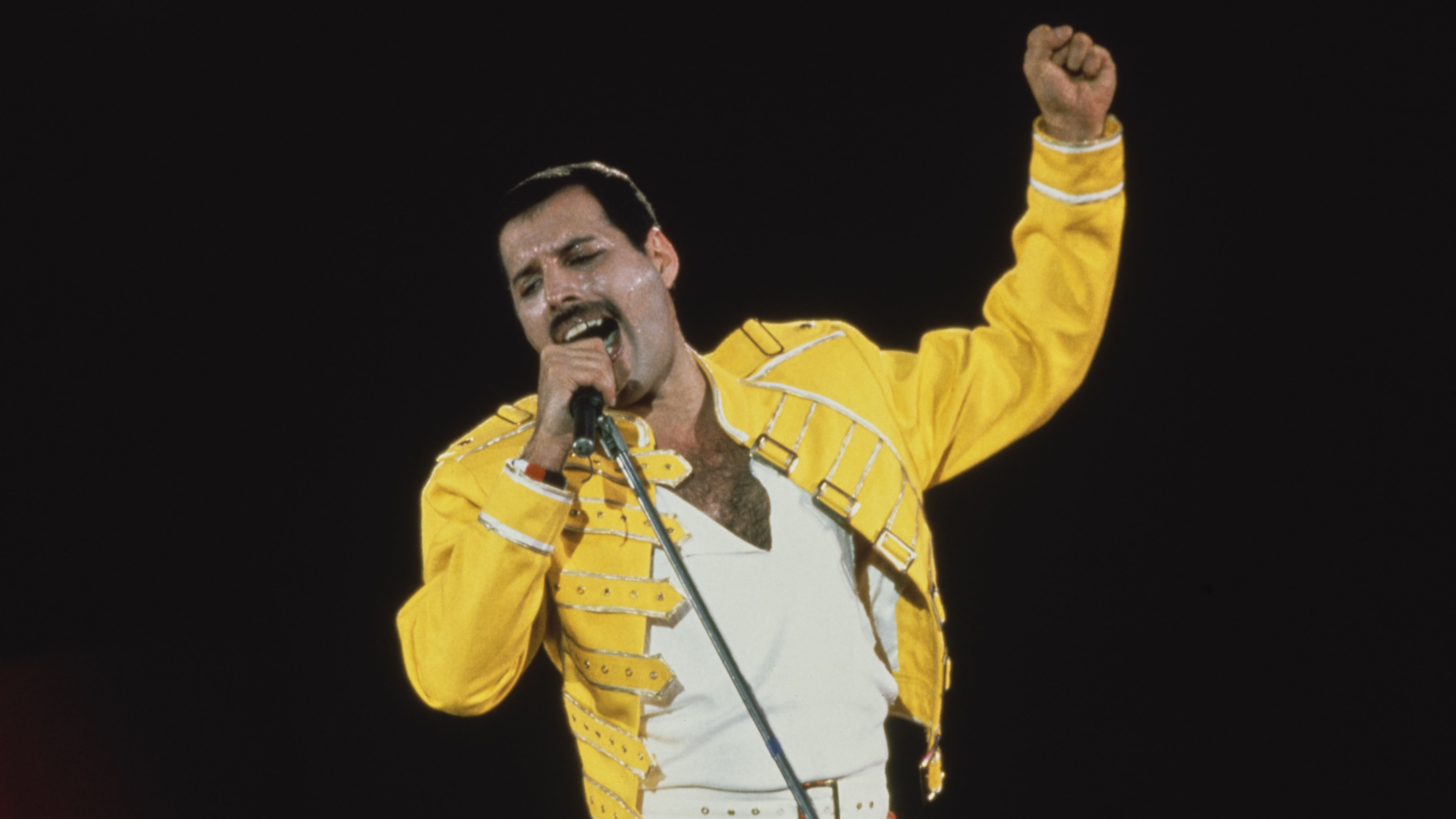 British singer-songwriter Freddie Mercury performing with Queen at Wembley Stadium, London, July 1986. The band played two nights at the venue, as part of the Magic Tour.