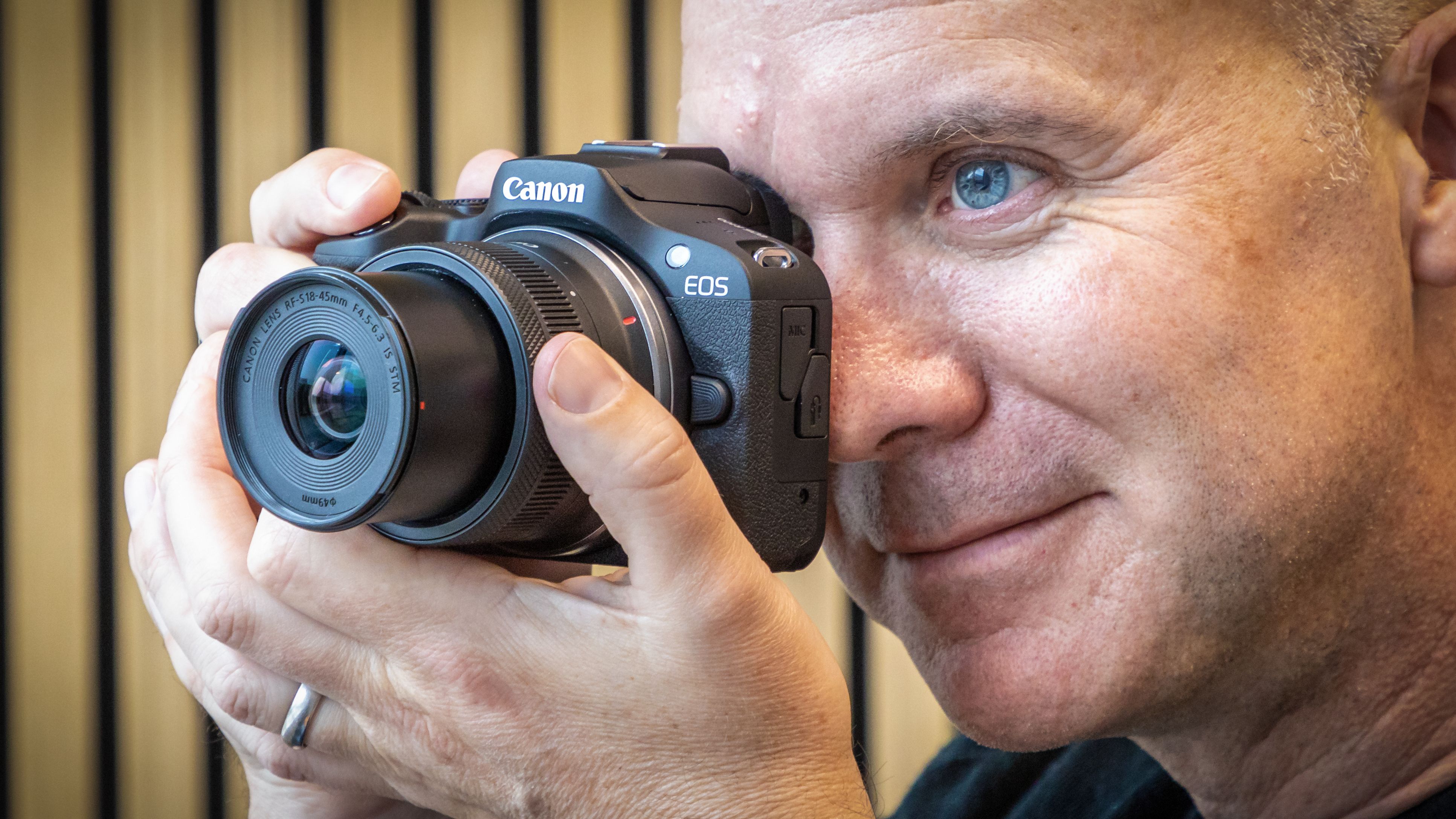 Peter Travers holding the Canon EOS R100 camera