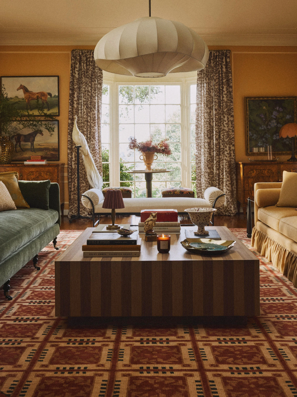 Richly layered fall living room featuring jewel-toned sofas, a striped coffee table, equestrian wall art, and several portable lamps.