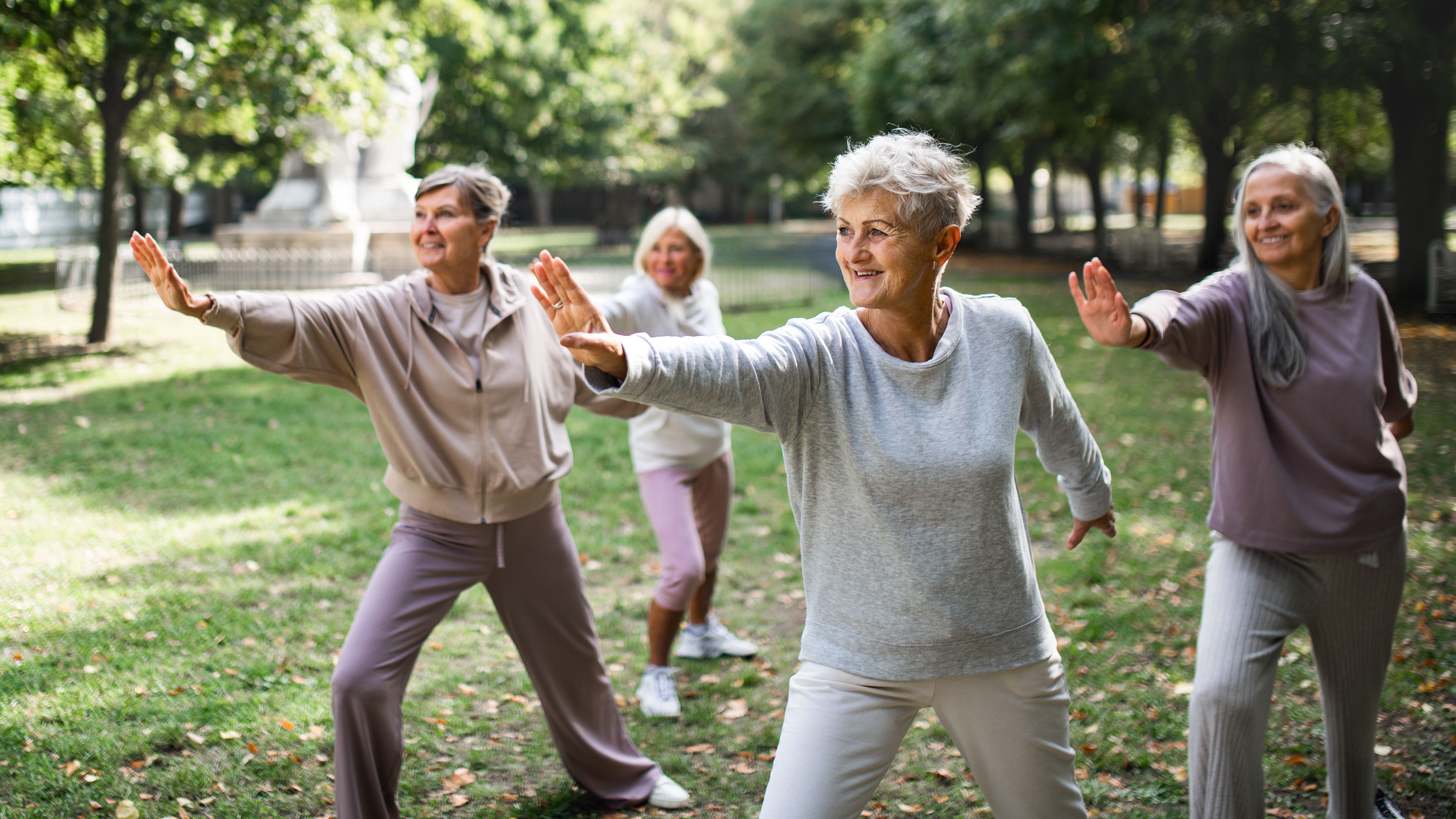 Four senior women practicing tai chi in a park