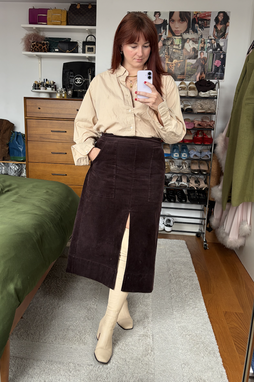 Tyler McCall in a mirror selfie wearing a tan button-down shirt, brown corduroy skirt, and white leather boots