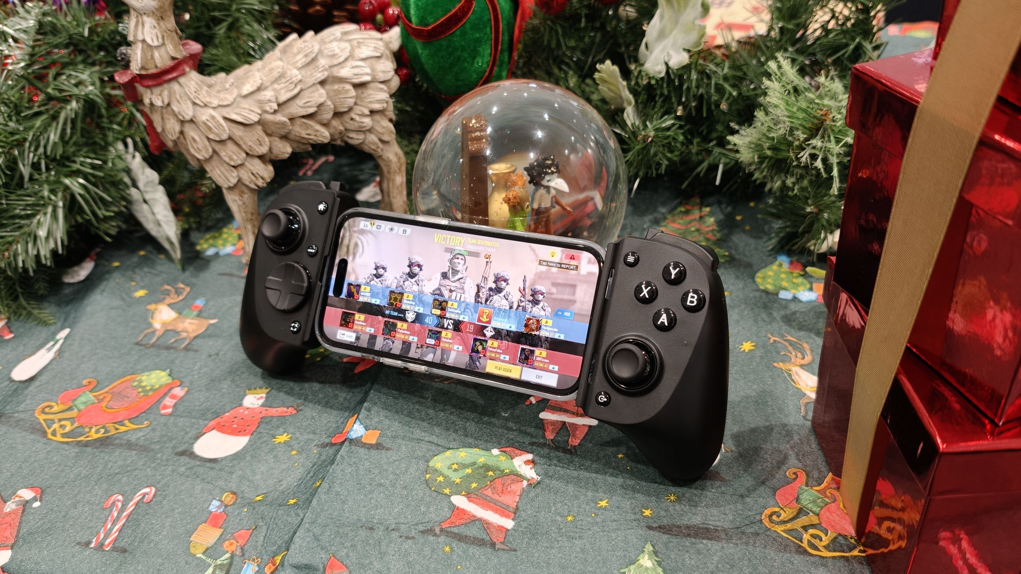 Razer Kishi V3 Pro resting on a snowglobe, with holiday items around