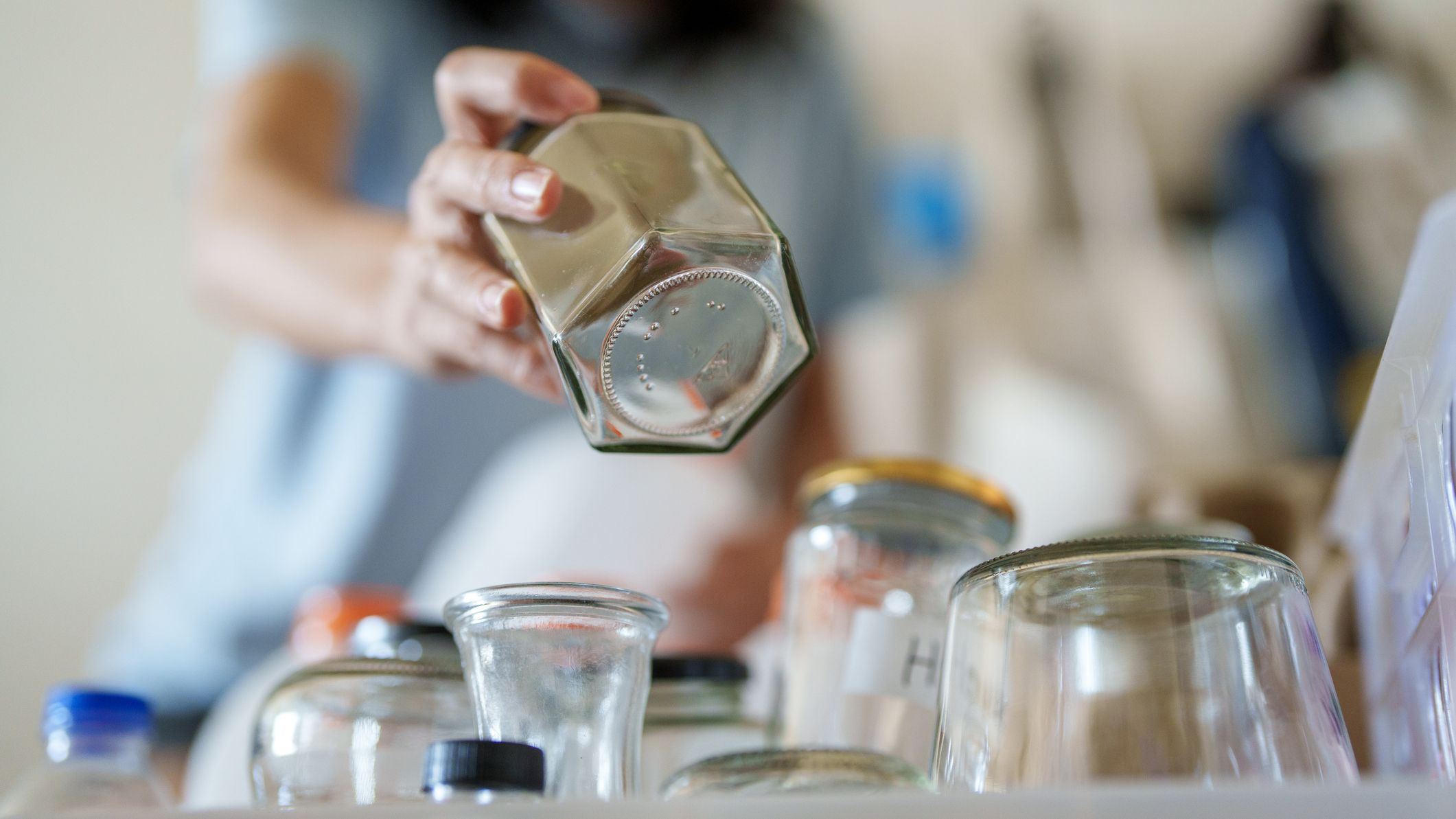 A woman adds an empty jar to a pile of empty jars in her kitchen.