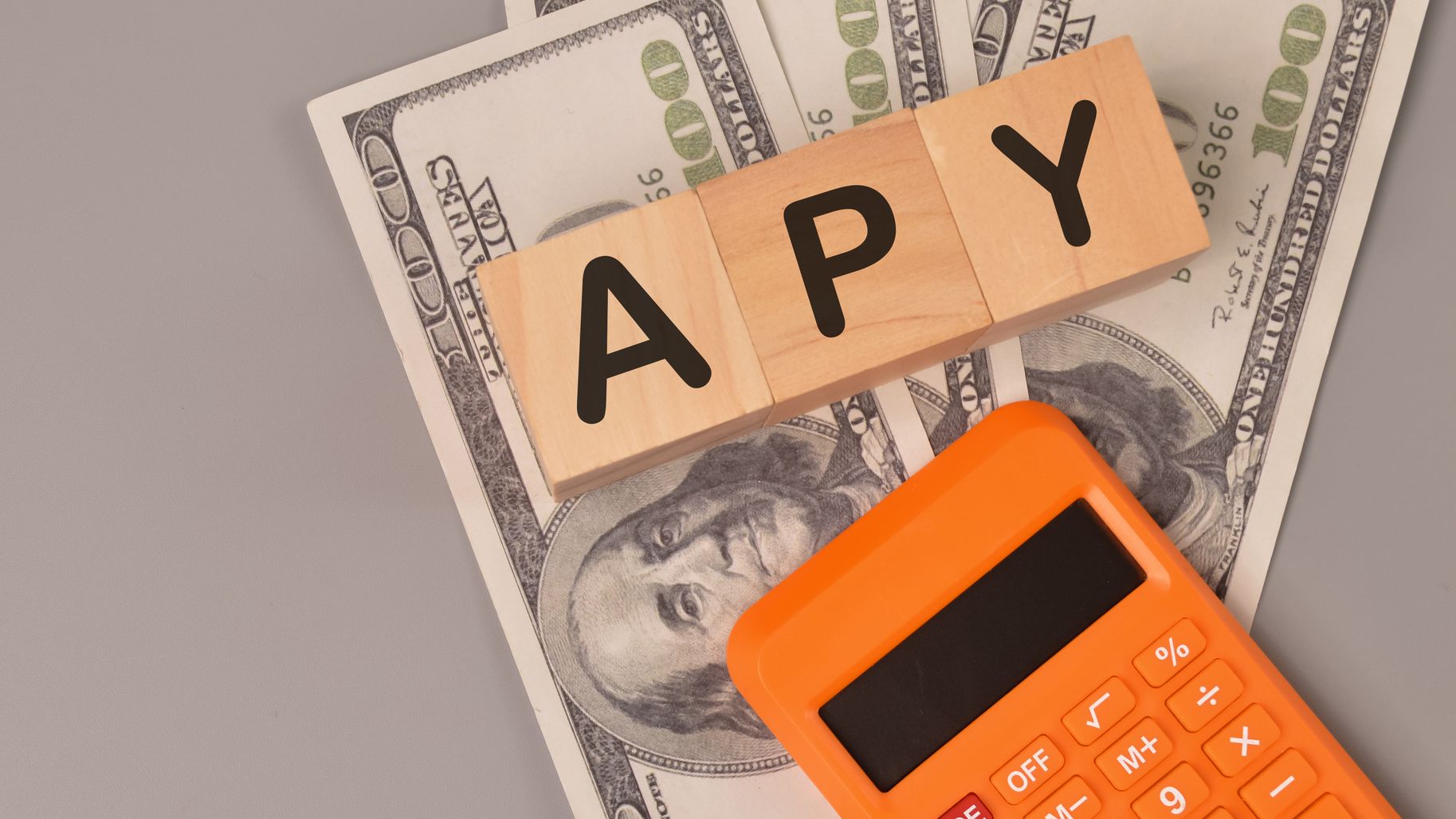 Money banknotes, calculator and wooden blocks written with APY.