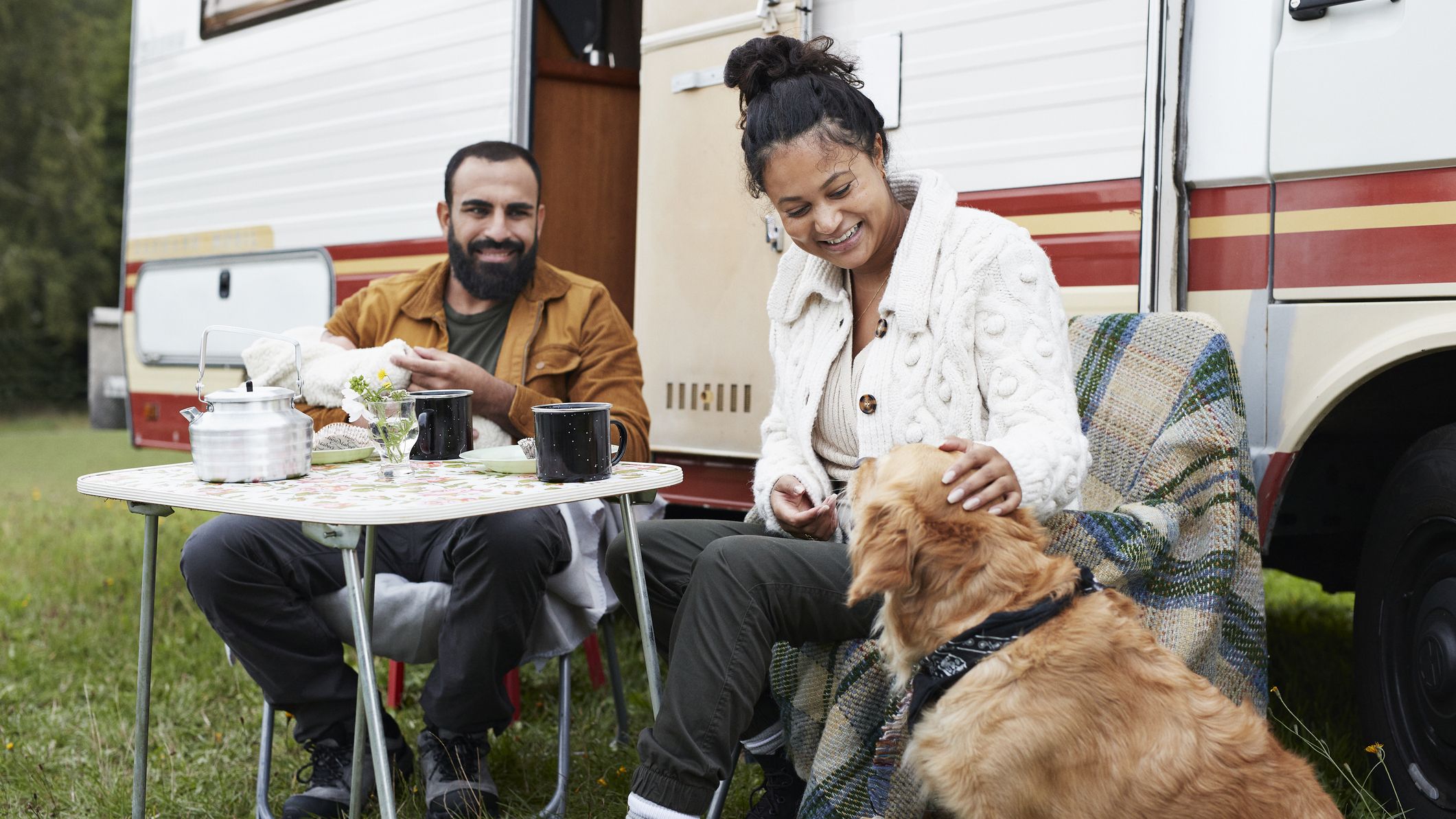 Happy family with dog spending leisure time outside motor home during vacation