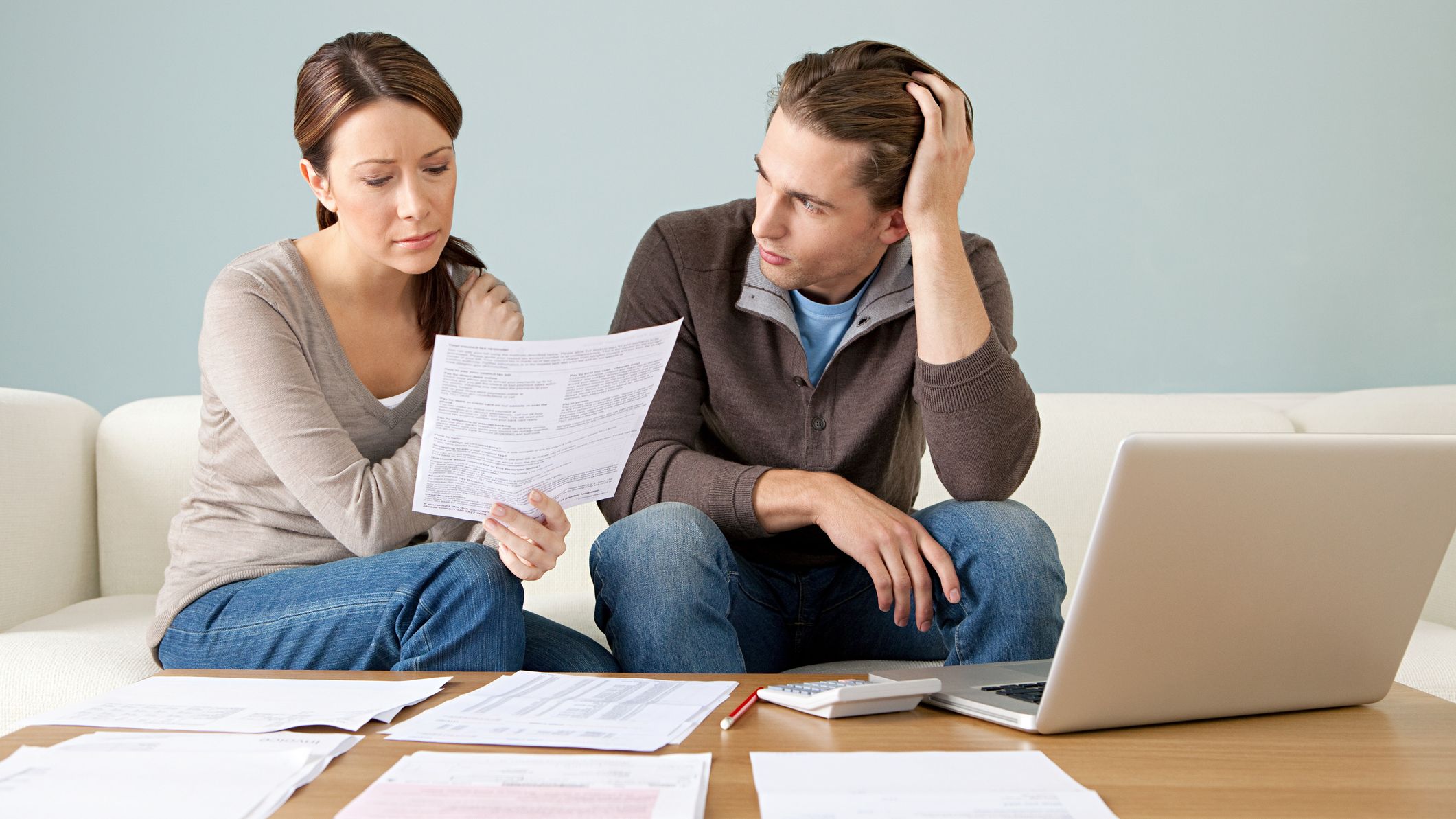 A couple discussing their home budget with paperwork and a laptop on the table.
