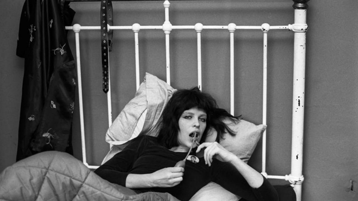 a black and white image of Judy Nylon in 1976 sitting on a bed
