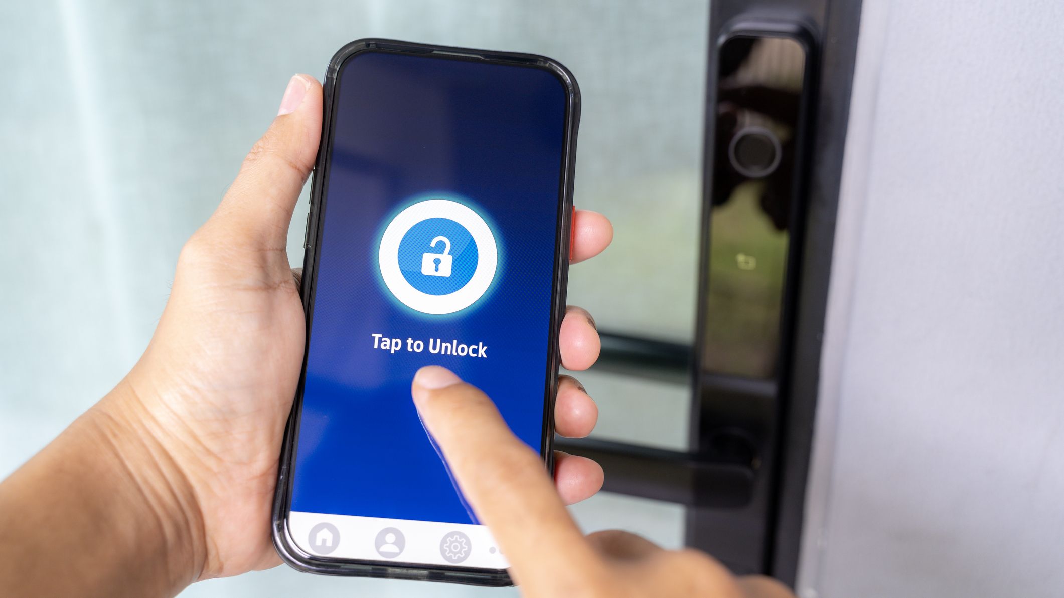Hand using smartphone application to unlock modern smart home door system