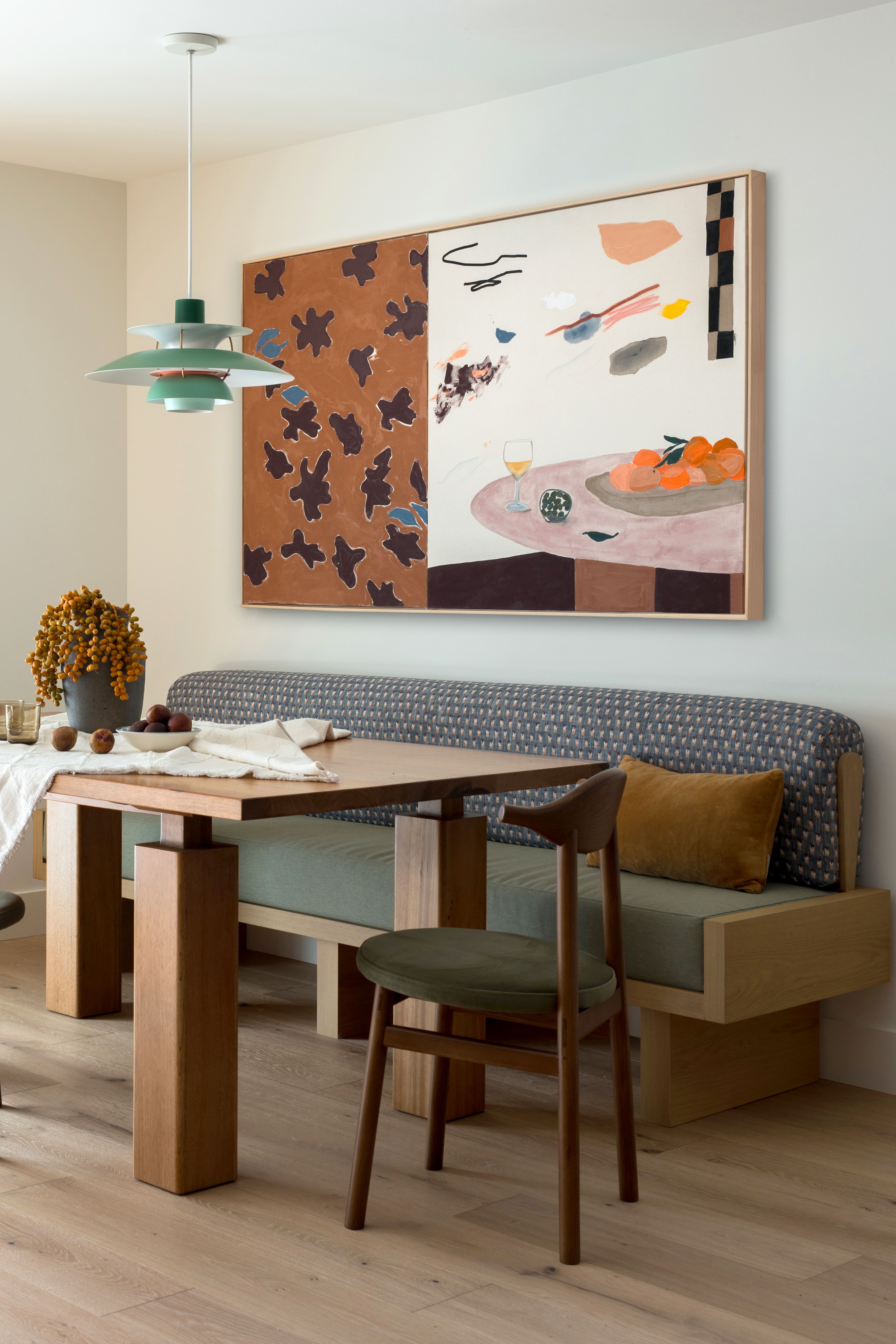 Custom wooden banquette with patterned backrest and plain seat fabric, angular wooden table and vintage chairs