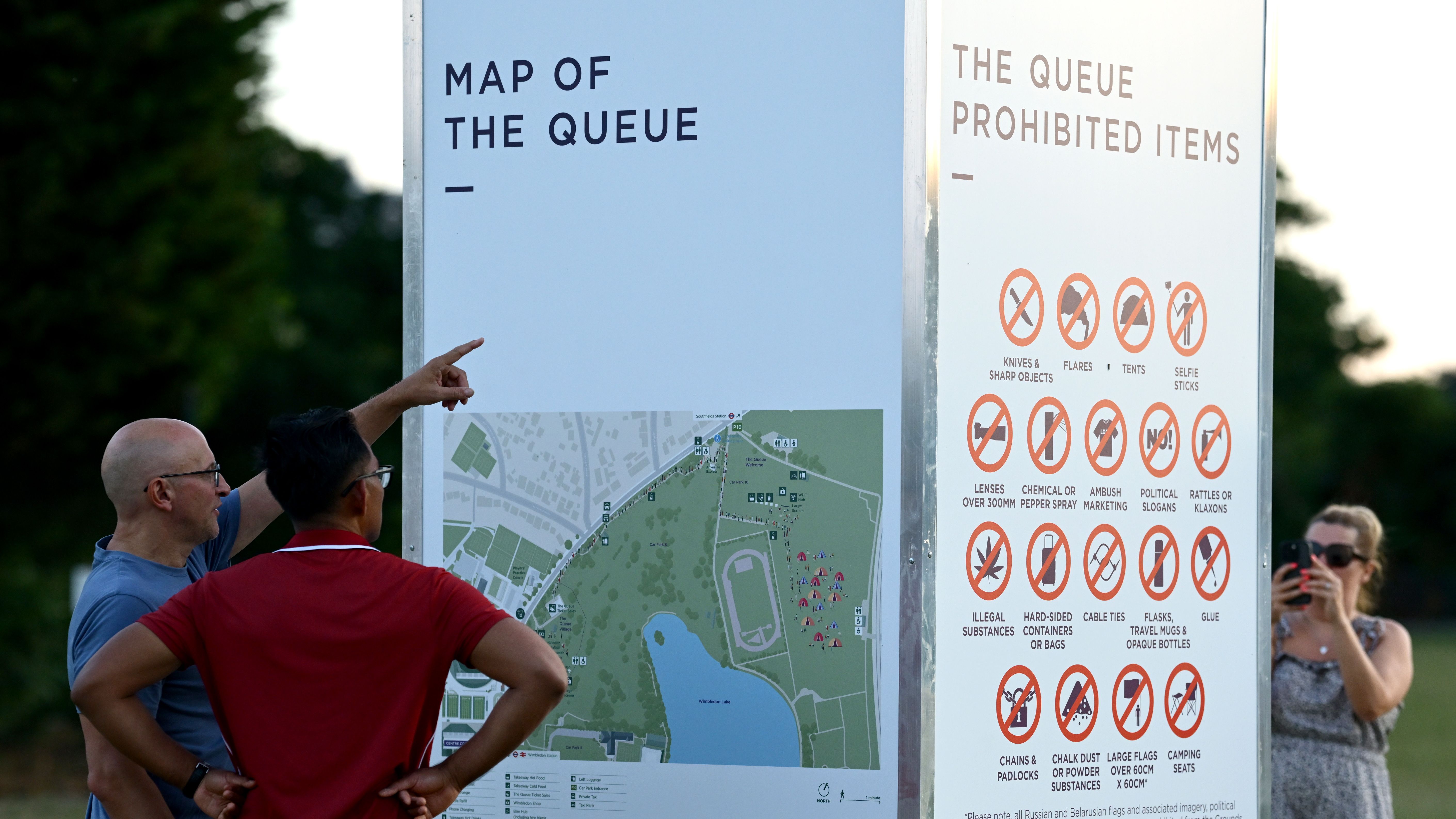 Spectators read the map for The Queue in Wimbledon Park the night before the start of The Championships Wimbledon 2025 at All England Lawn Tennis and Croquet Club