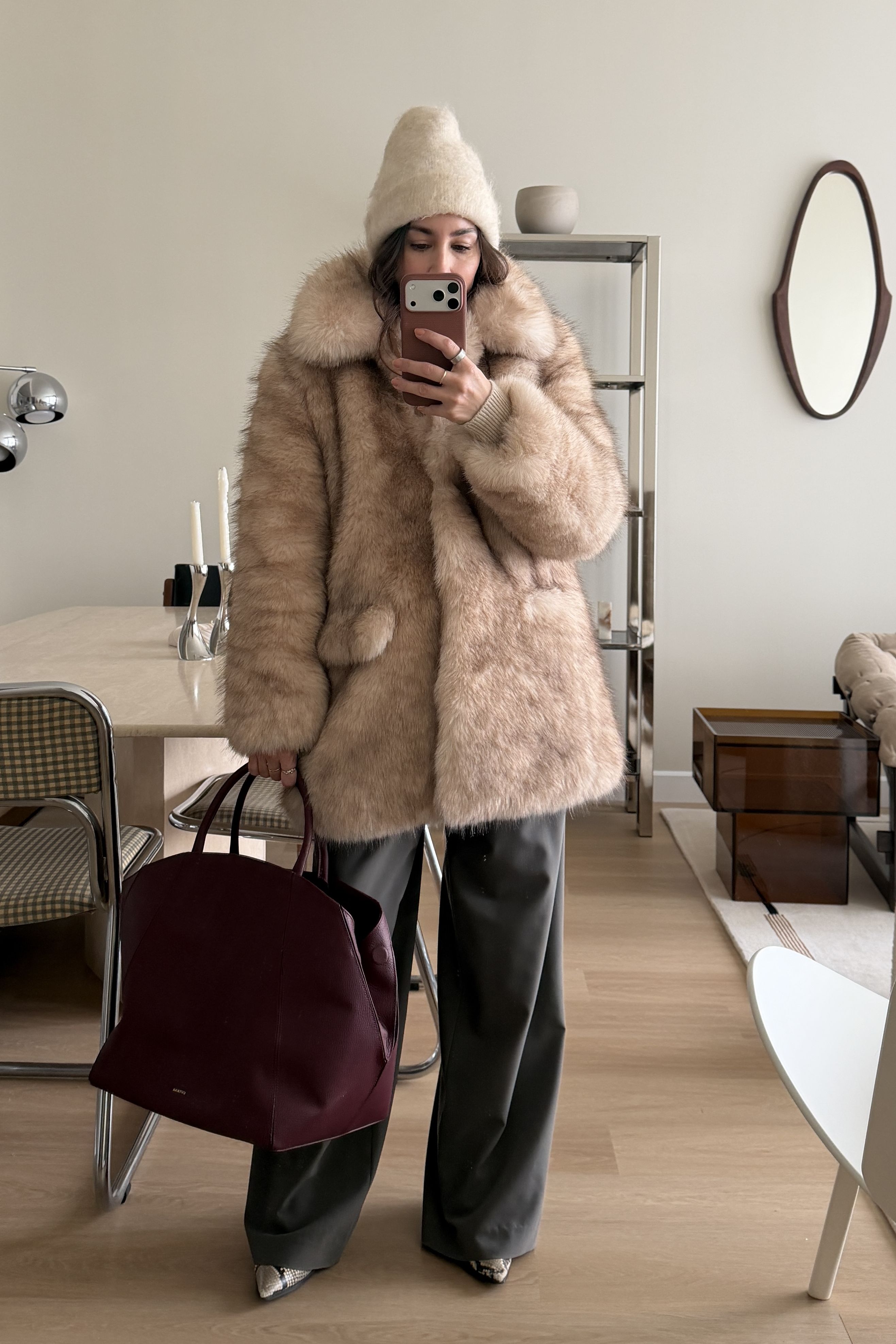 Lauren Caruso posing in mirror wearing beanie, fur coat, and purple tote bag