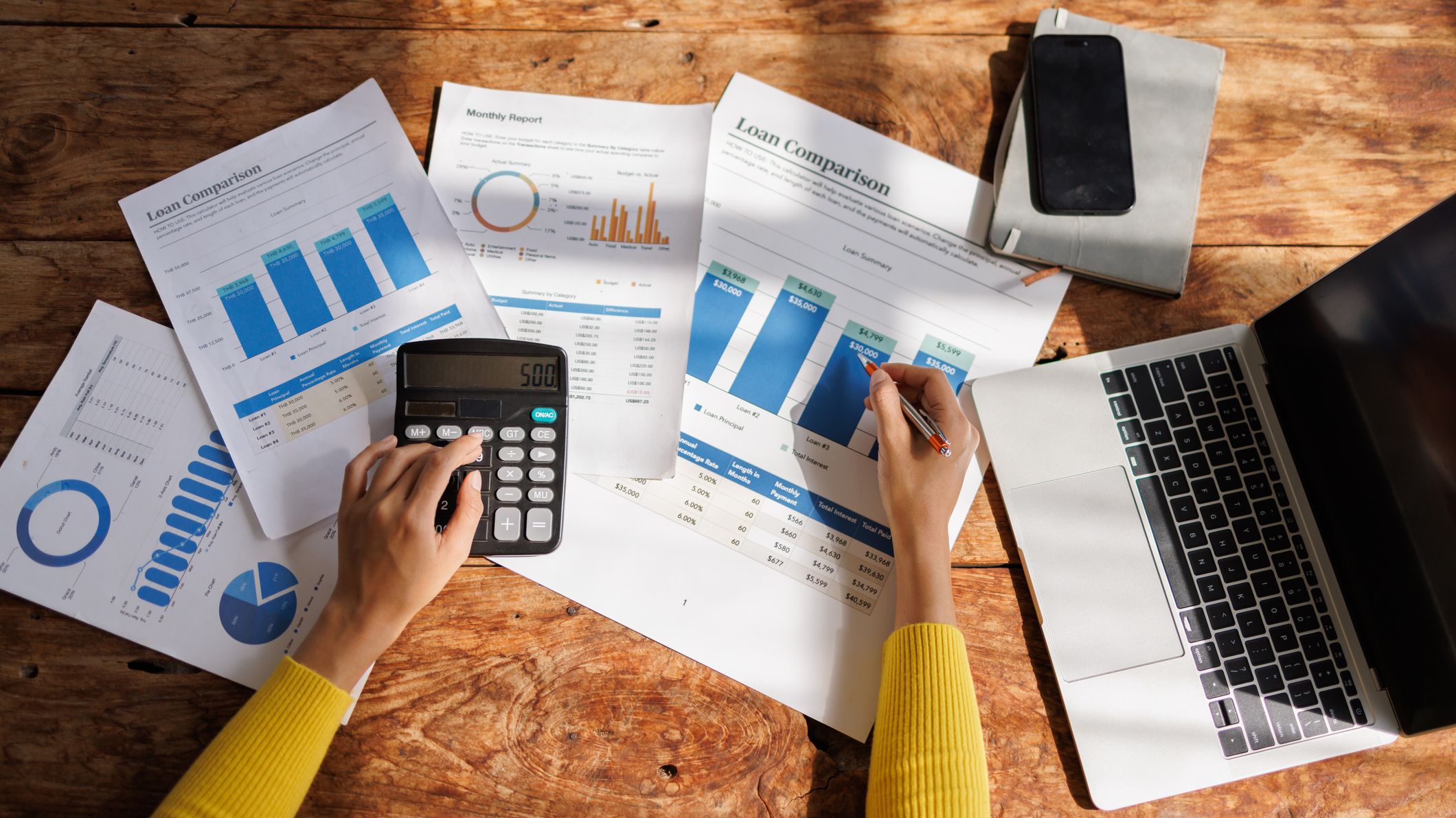 Person calculating loan comparison data using calculator and laptop