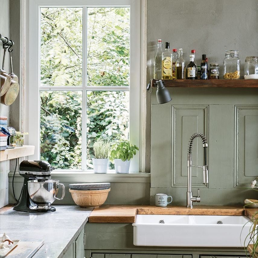 Corner of a farmhouse style kitchen with double ceramic sink and view through window
