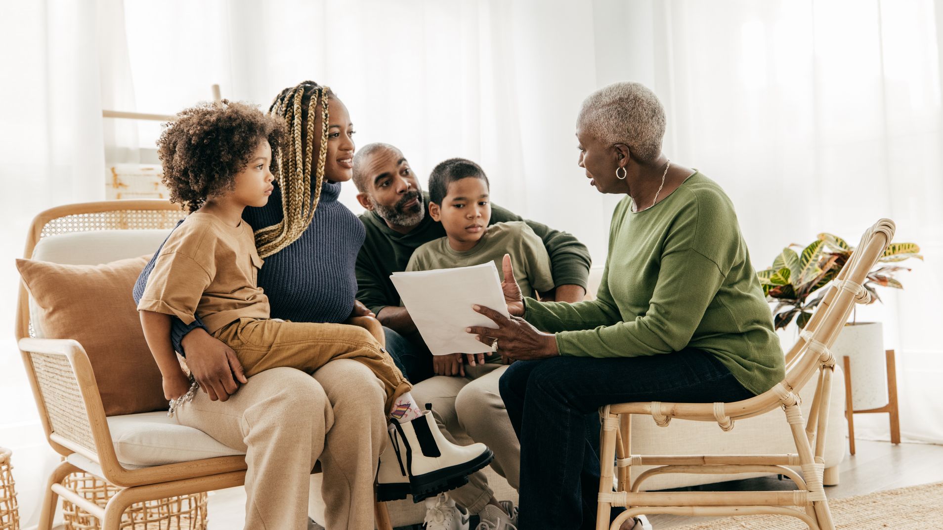 A senior woman reviews financial paperwork with her family in her living room.