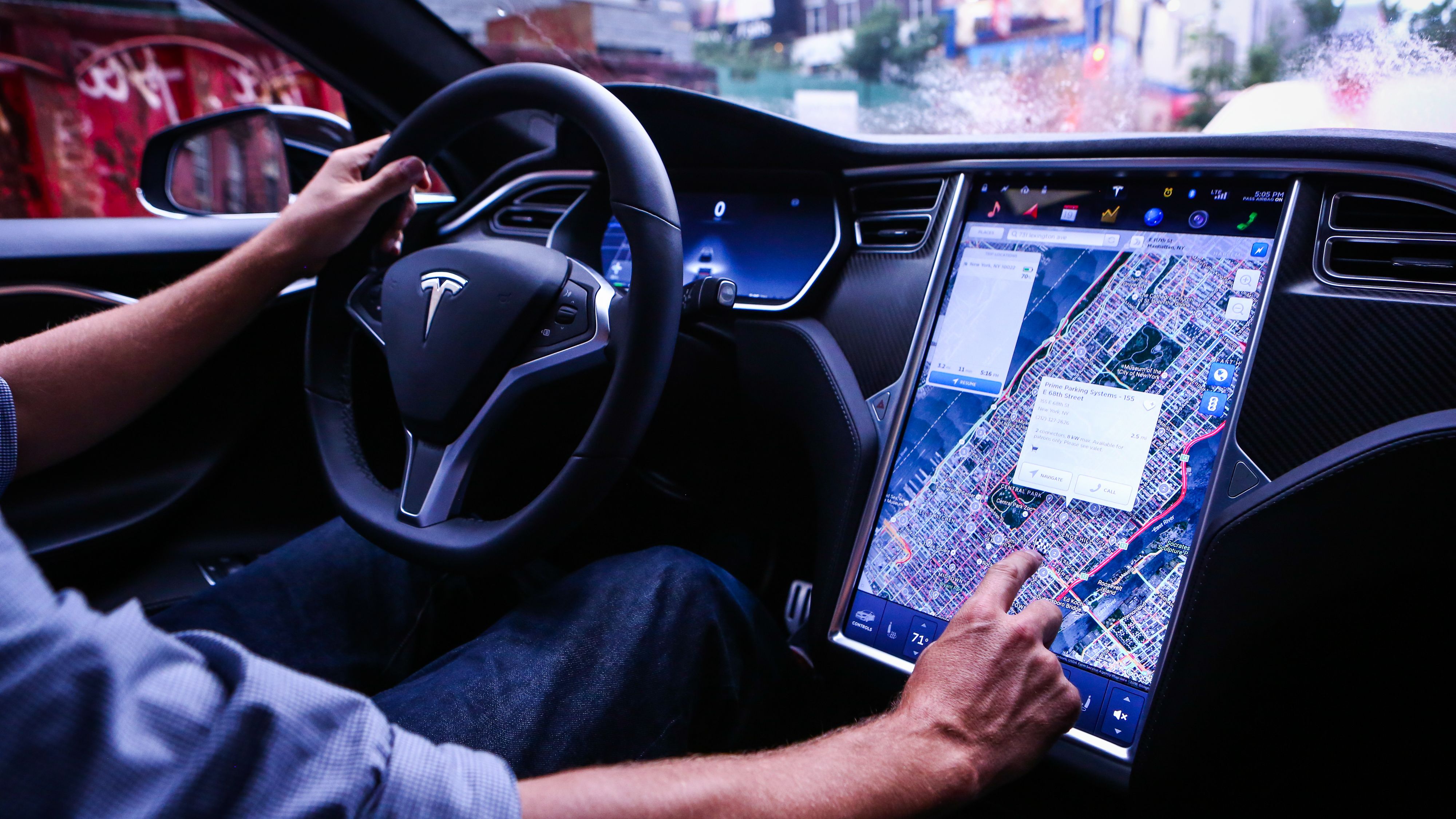 A driver adjusts the map on the touchscreen while driving in a Tesla.
