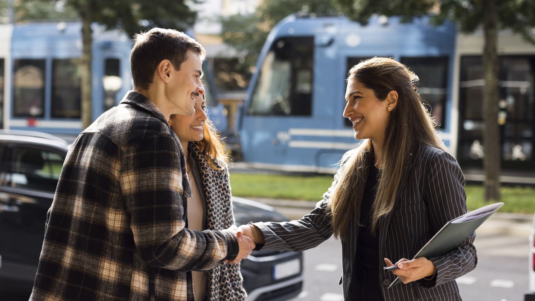 Smiling man doing handshake with female real estate agent while standing at street