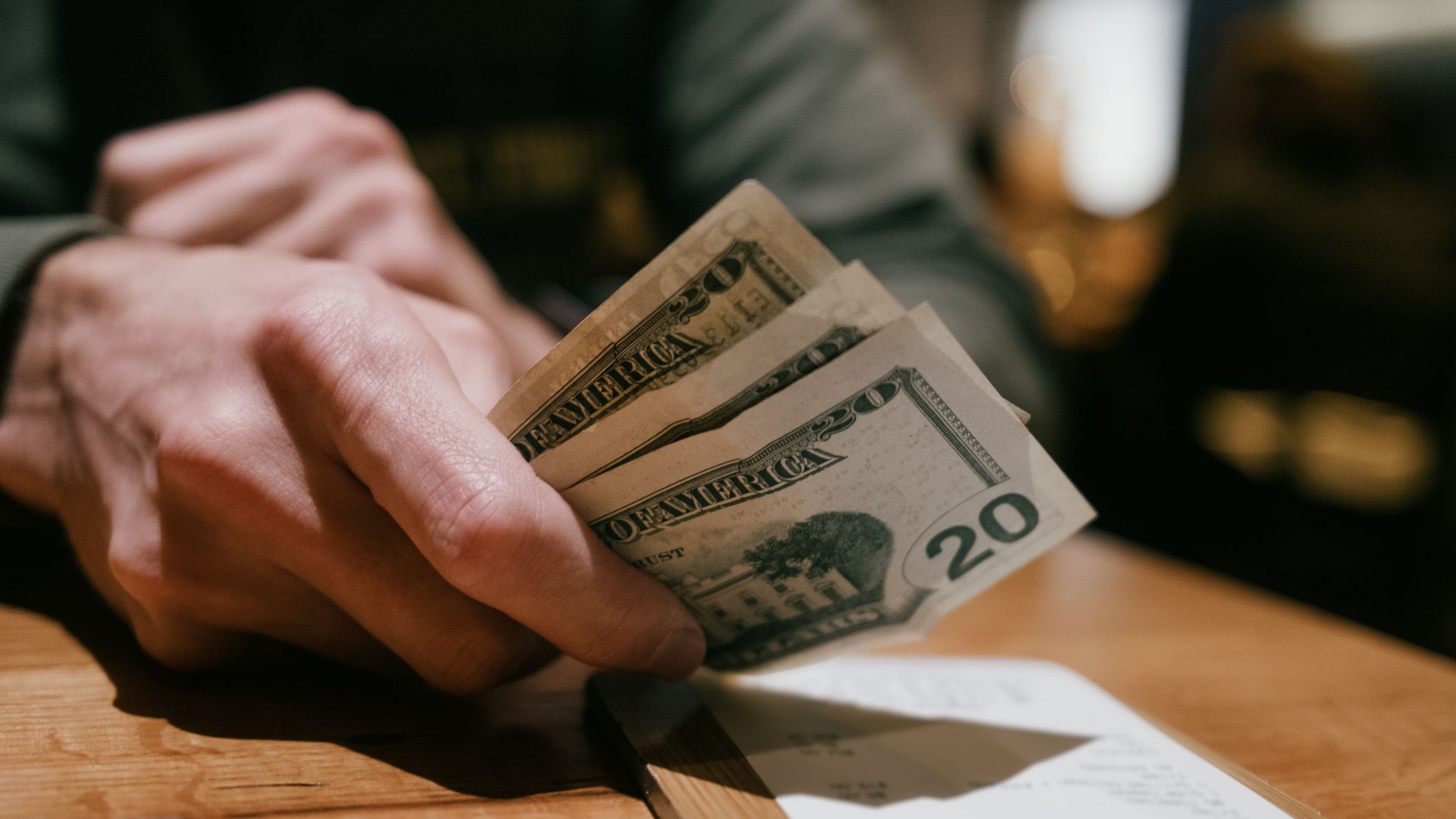a man lays down three $20 bills to pay a restaurant bill