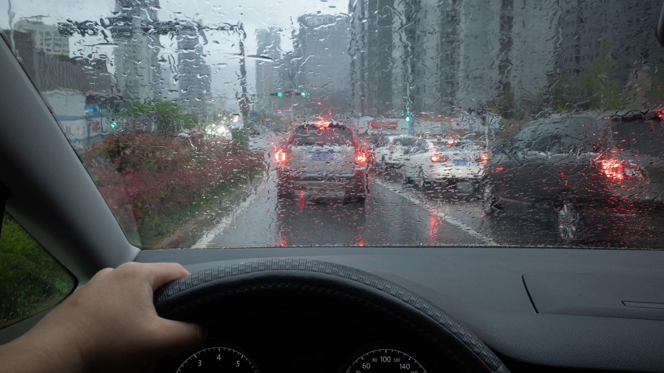 A driver's perspective of traffic in a city on a rainy day.