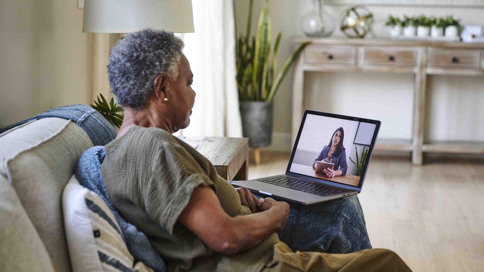 Woman sitting on a couch having a video call on a laptop