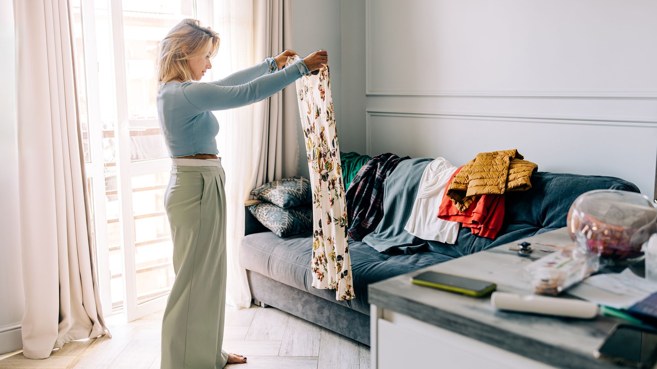 Mid adult woman organizing wardrobe and trying on clothes at home