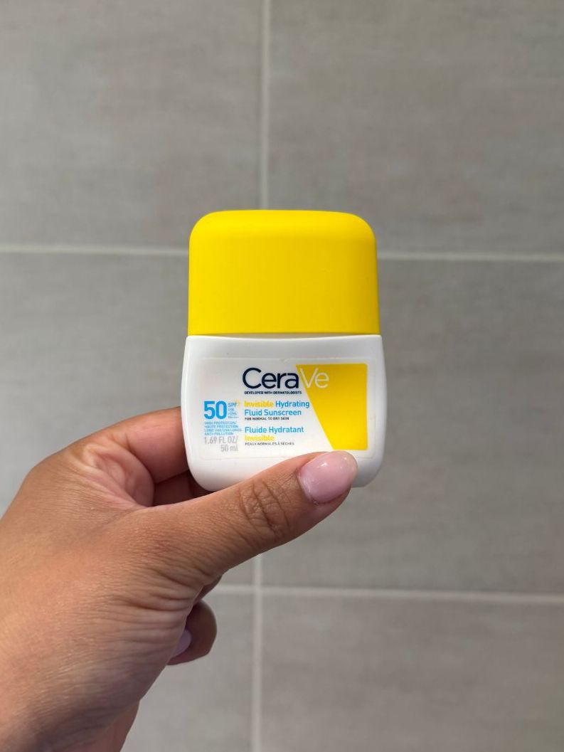 Aleesha holding empty Cerave Hydrating sunscreen