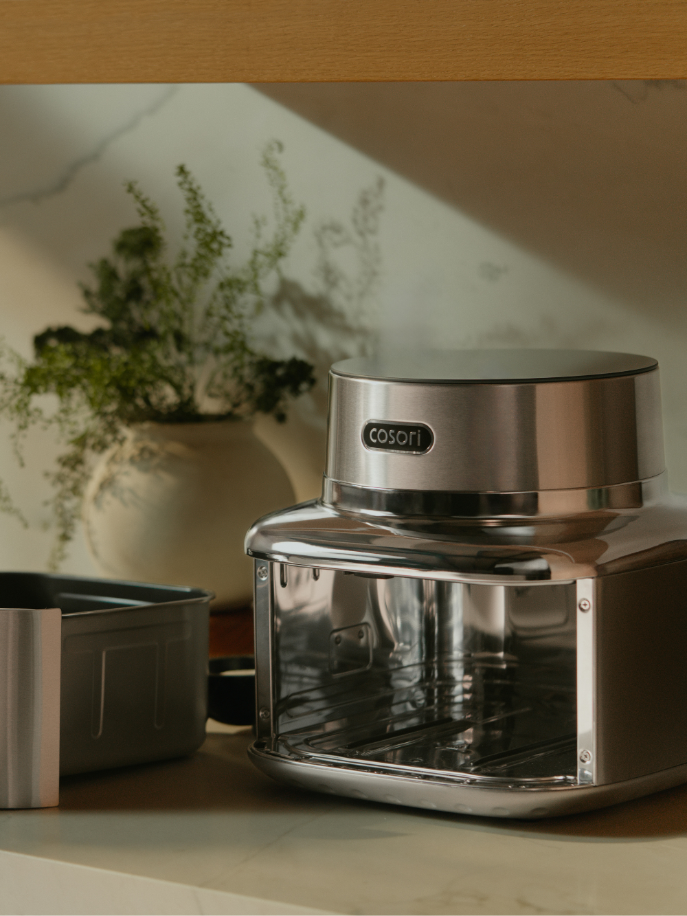 Stainless steel Cosori air fryer and air fryer drawer sitting on a kitchen counter