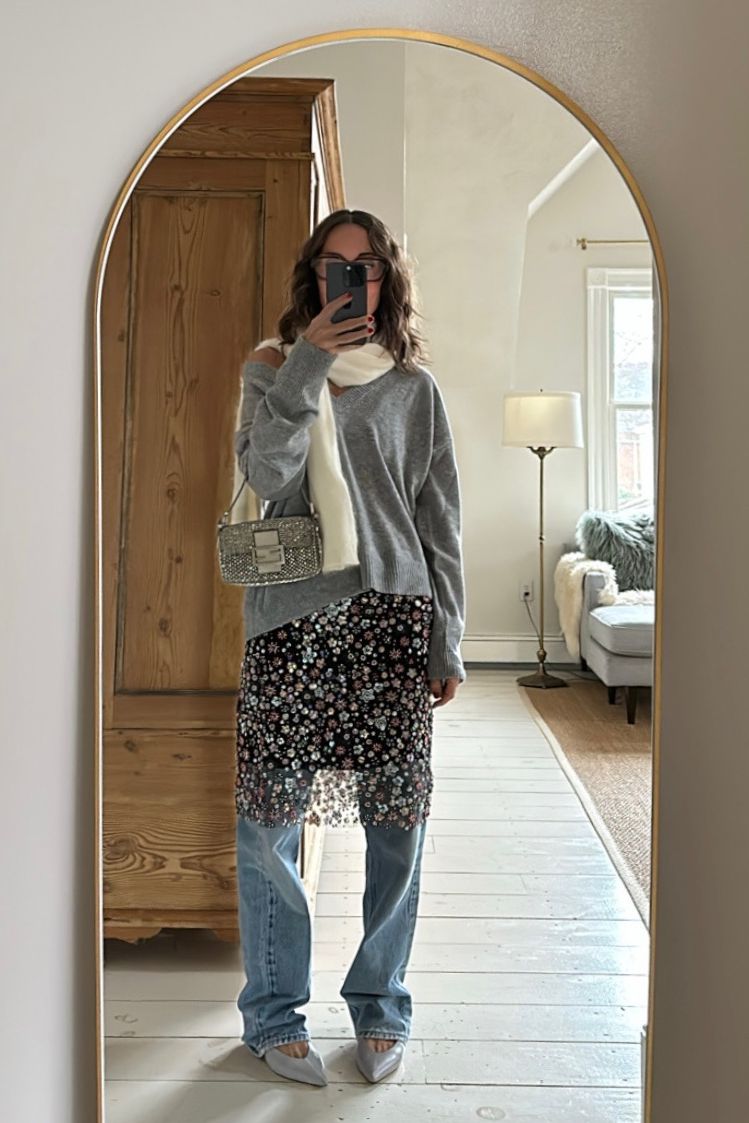 Larissa Mills wearing a black sequined sheer skirt with blue jeans, a gray sweater, and white scarf