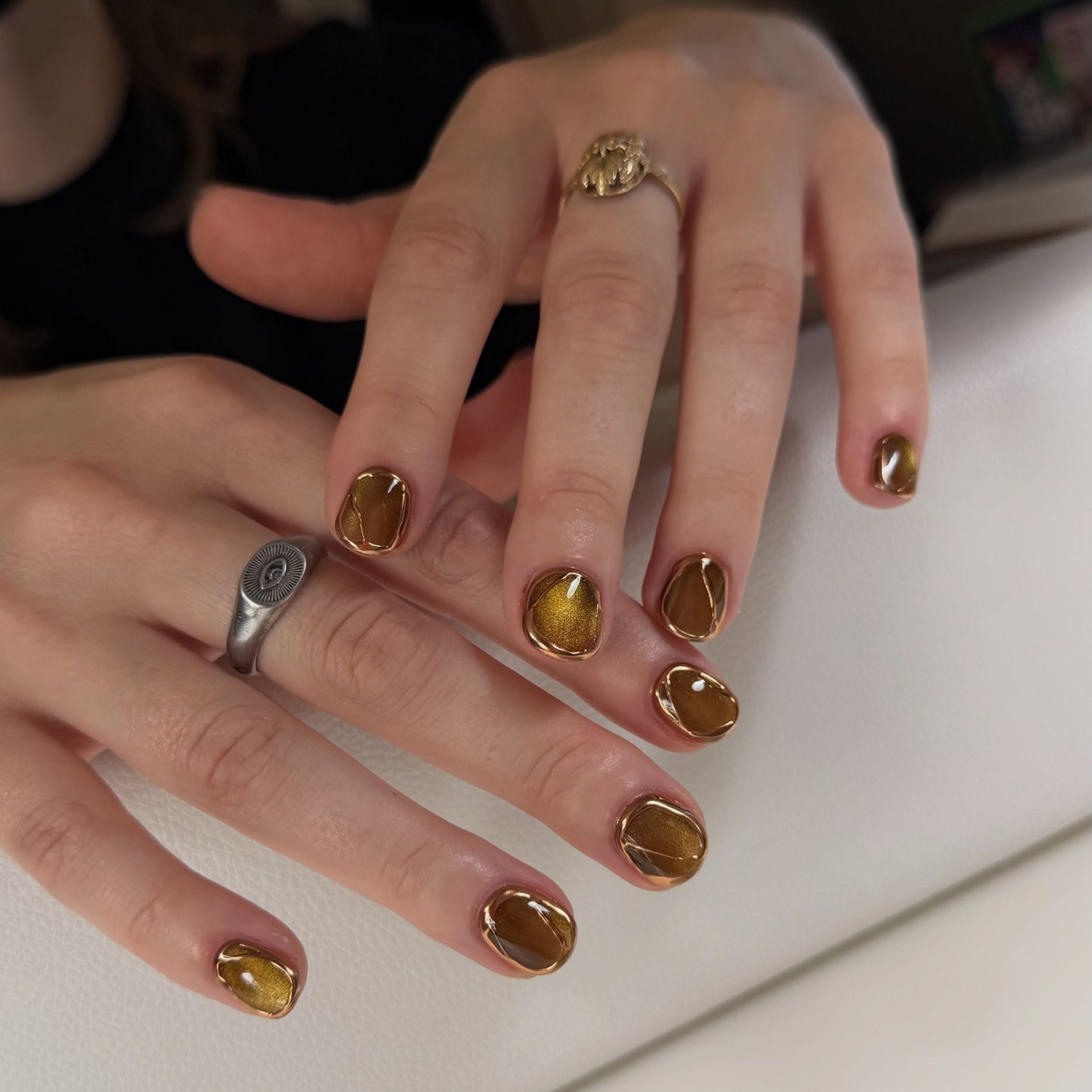 amber green nails with thin gold detailing around the edges of each nail